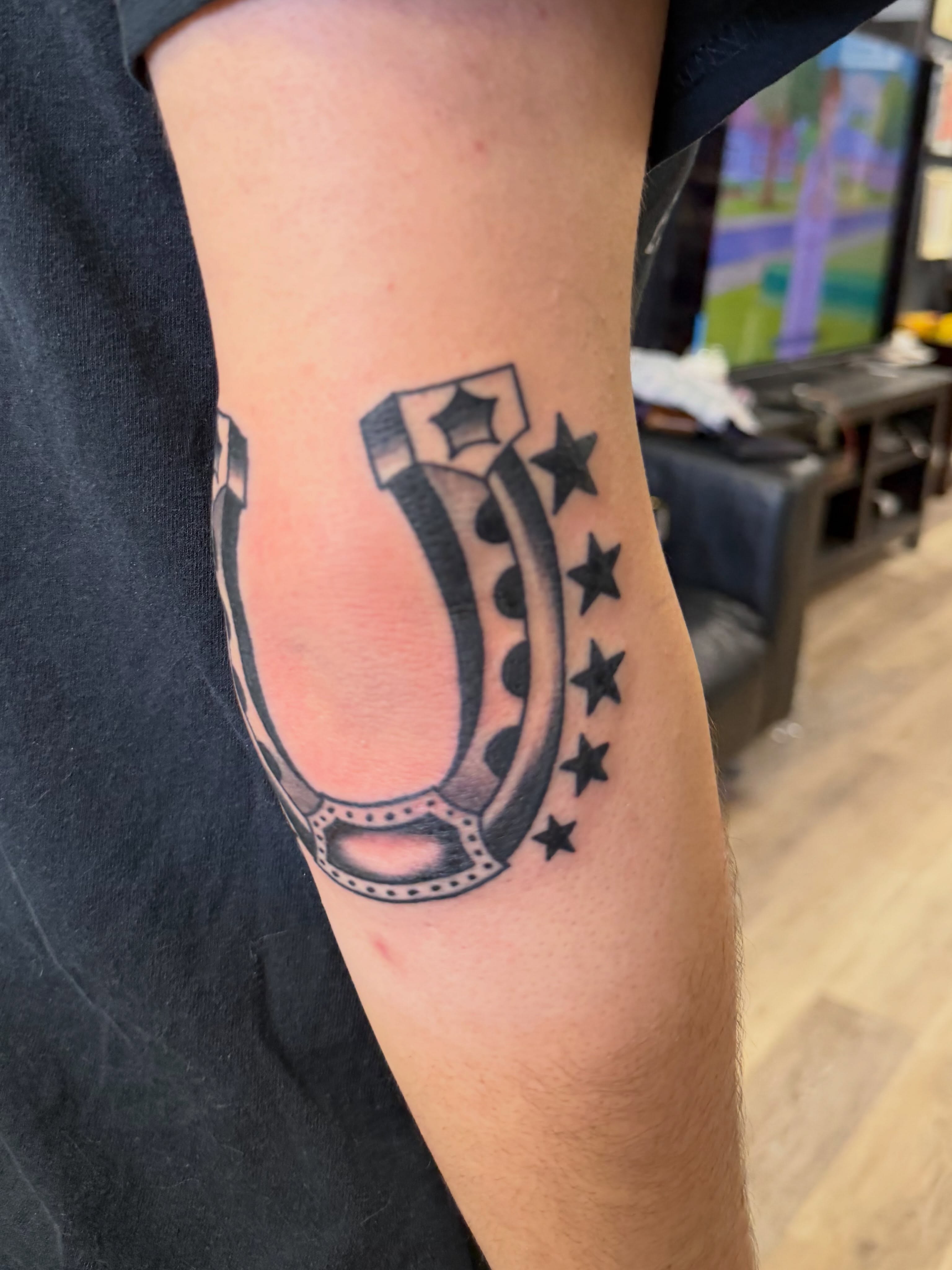 Horseshoe with stars black and grey tattoo on the forearm by Kane L, Albuquerque, New Mexico