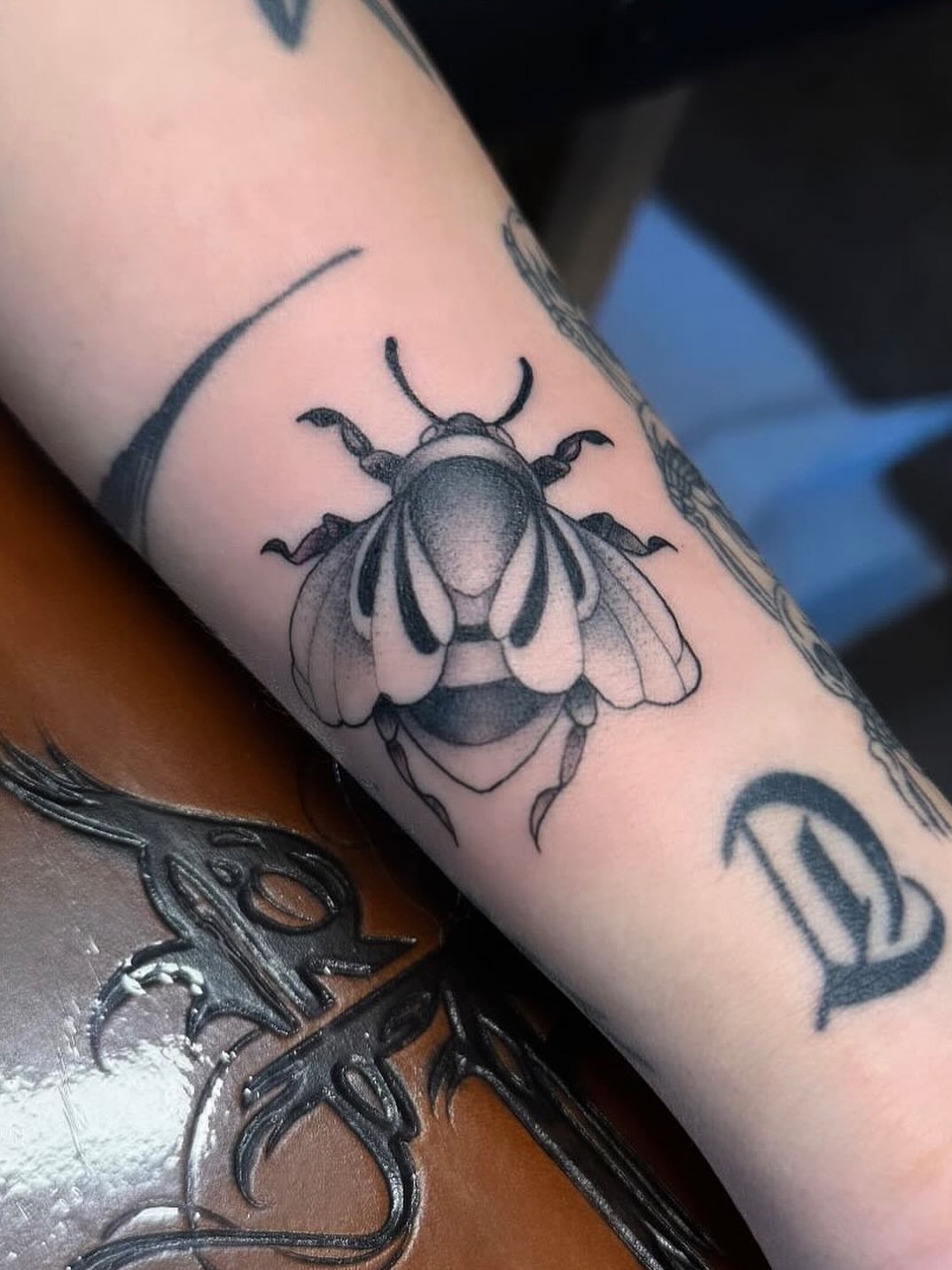 Bee black and grey tattoo on the forearm by Gabrielle Mack