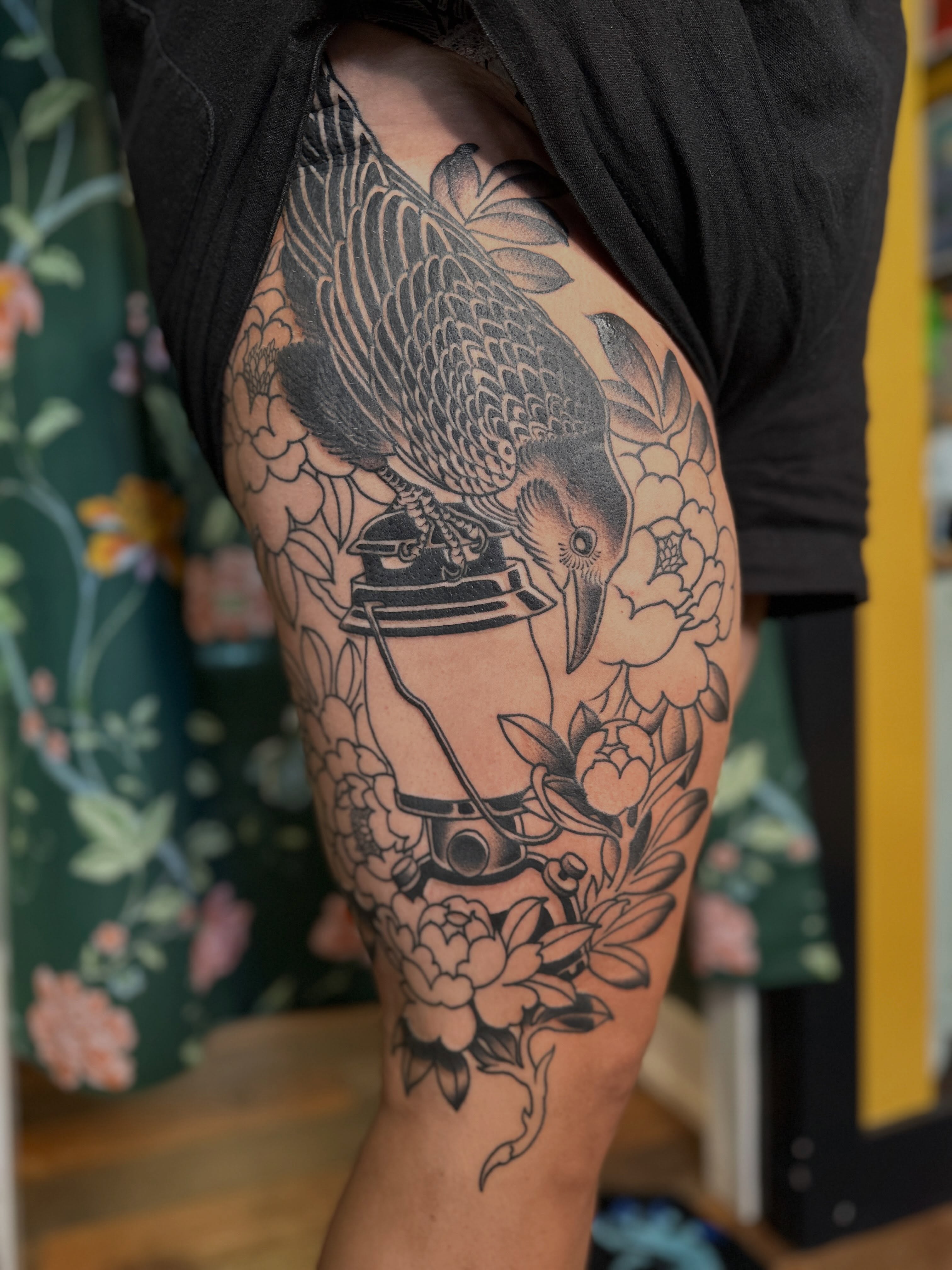 Crow and floral arrangement black and grey tattoo on the thigh by Megon Shore, Seattle, Washington