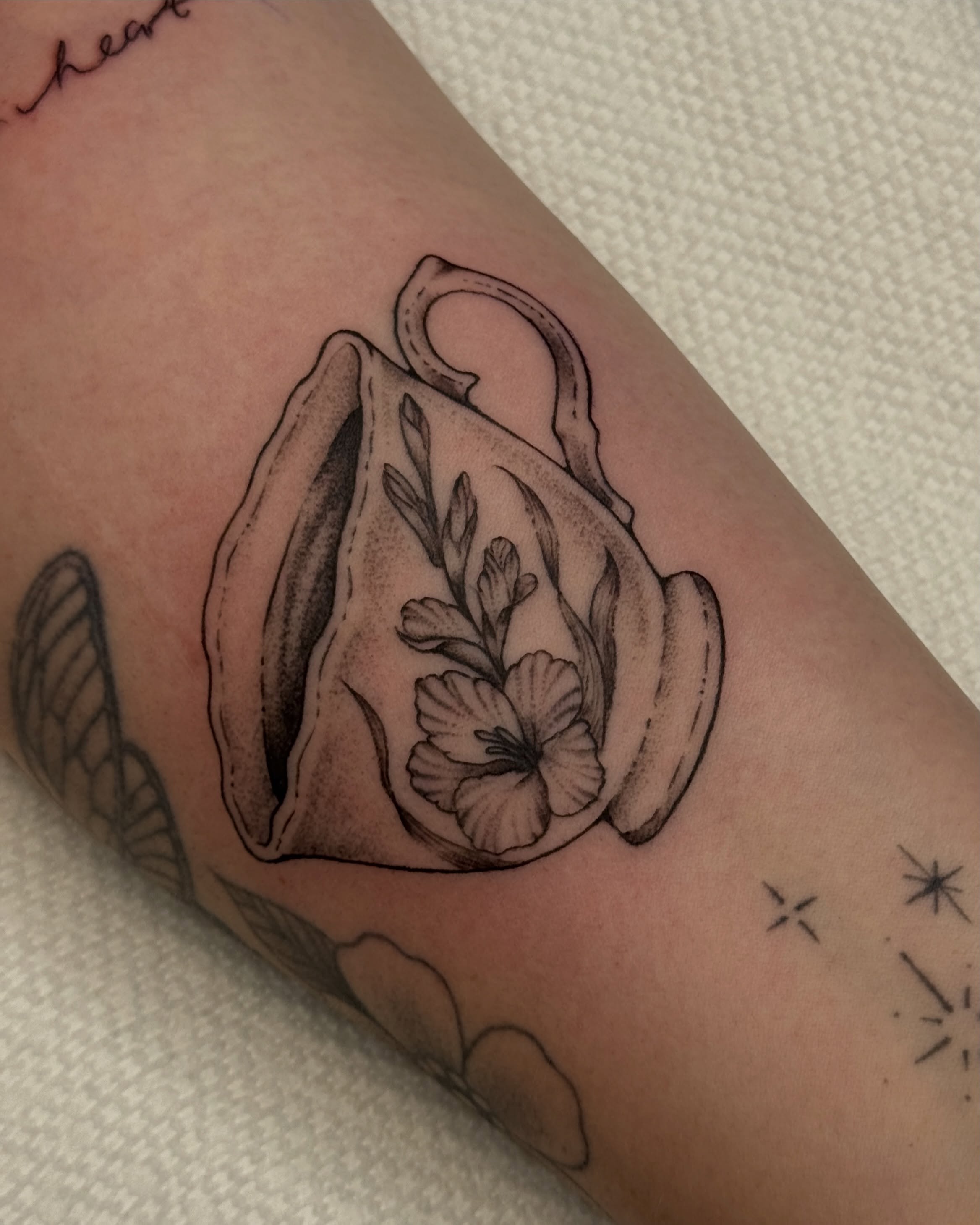 Teacup and flower black and grey tattoo on the forearm by Bre Grover, Vancouver, British Columbia