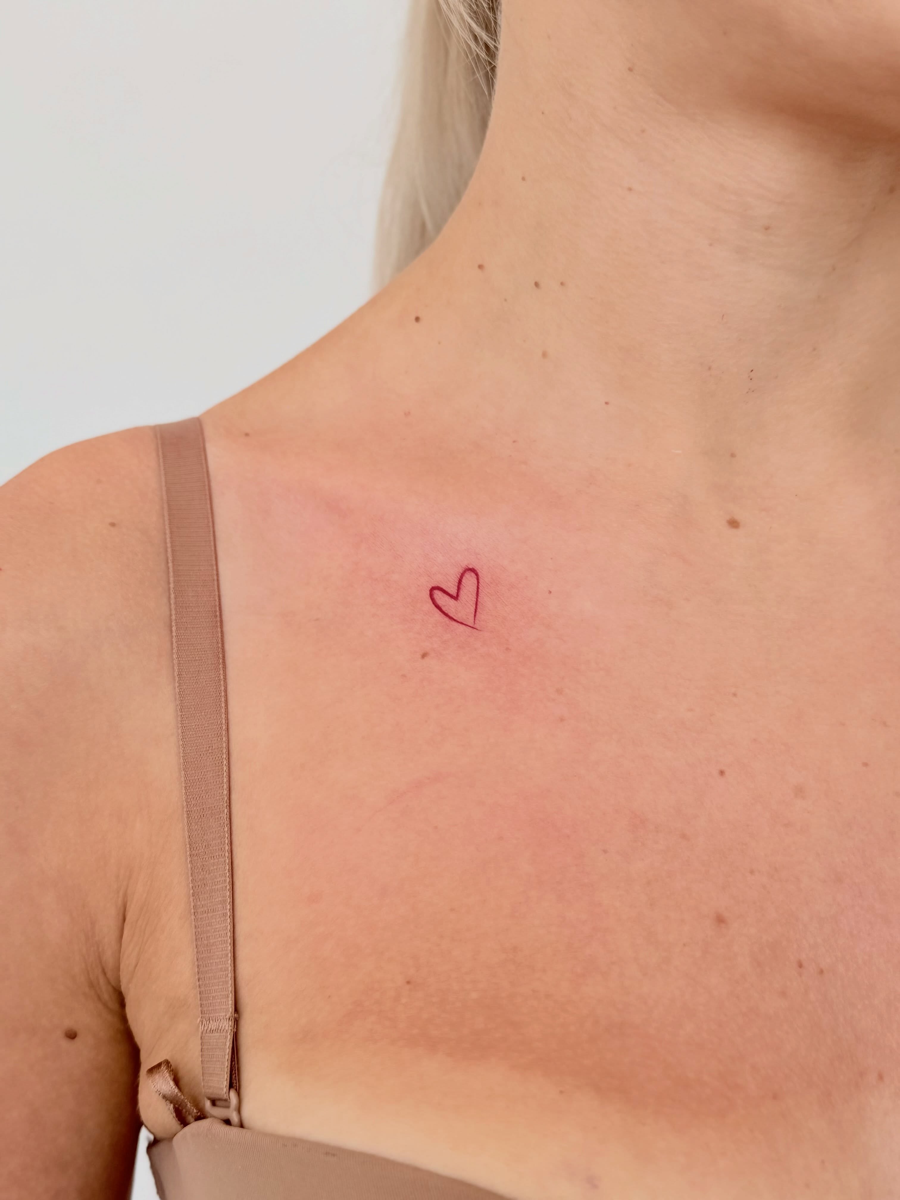Heart fine line tattoo on the chest by Fine Line Tattoo Artist
