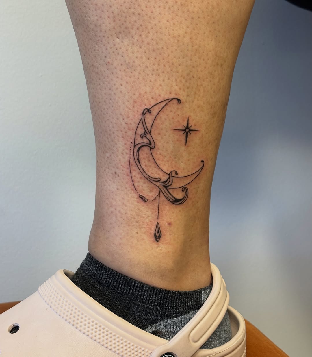 Moon and star fine line tattoo on the calf by Maddie