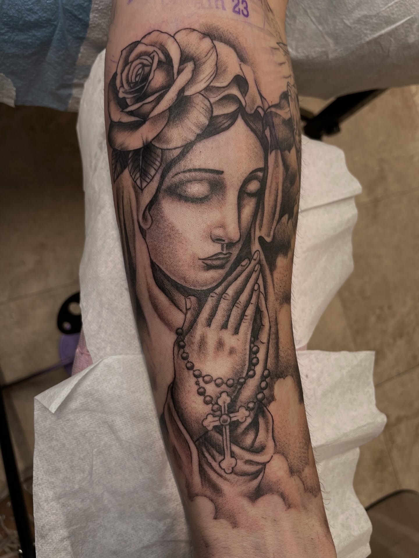 Praying woman with rose realism tattoo on the forearm by Gerald Bellmore
