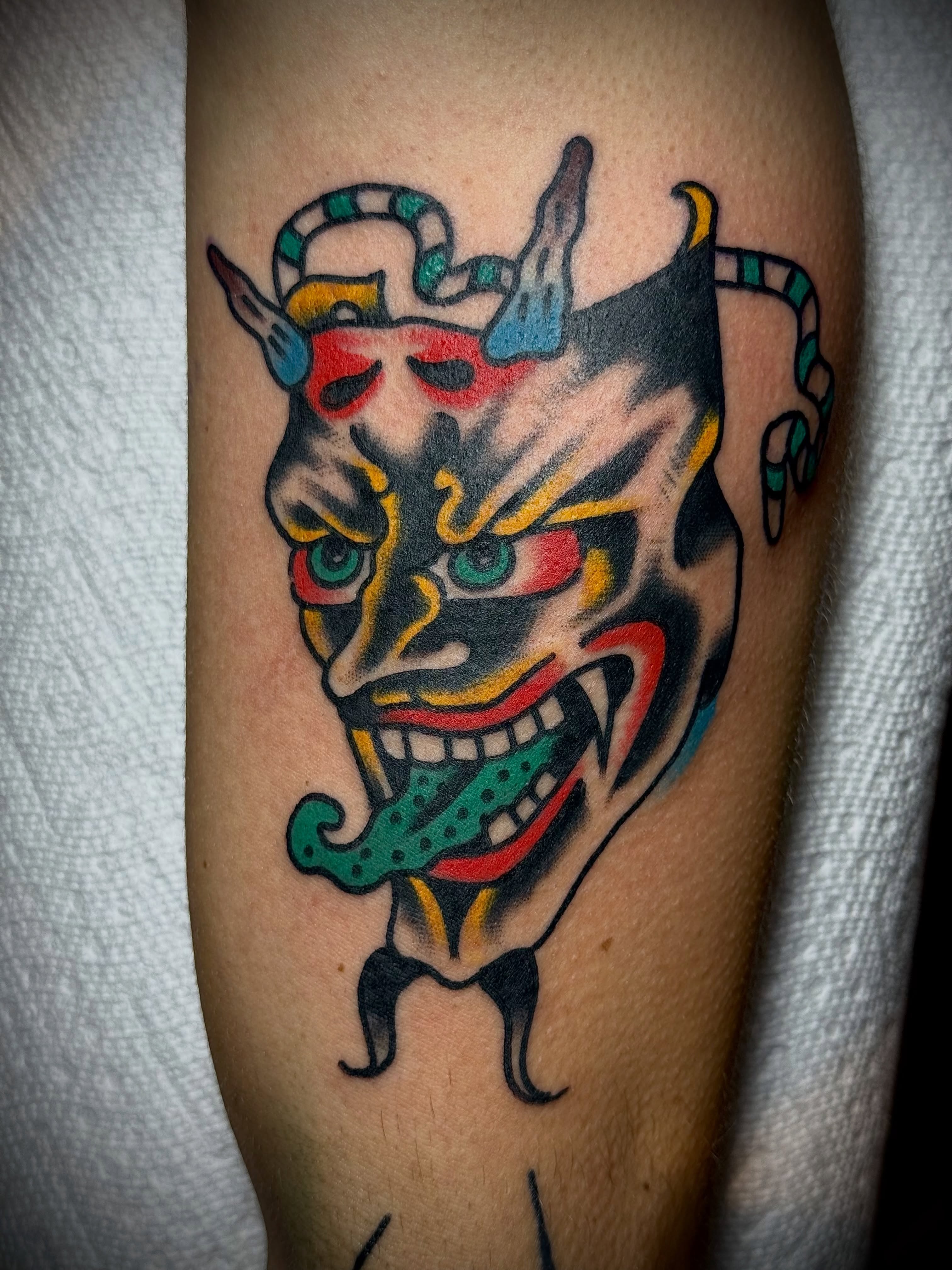 Demon mask American traditional tattoo on the forearm by Chuck Derek Whitaker