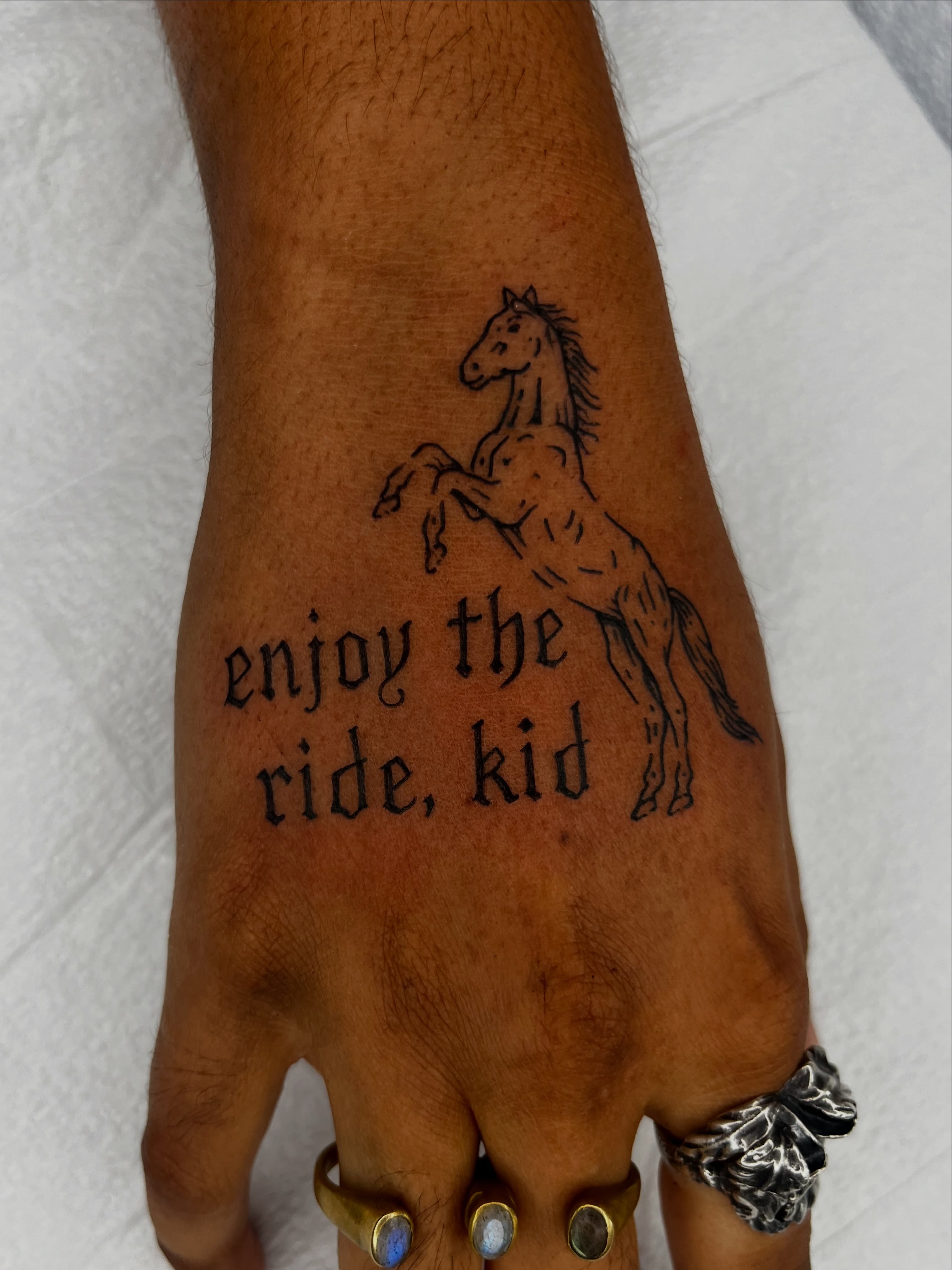 Horse and phrase black and grey tattoo on the hand by Patrick Elijah