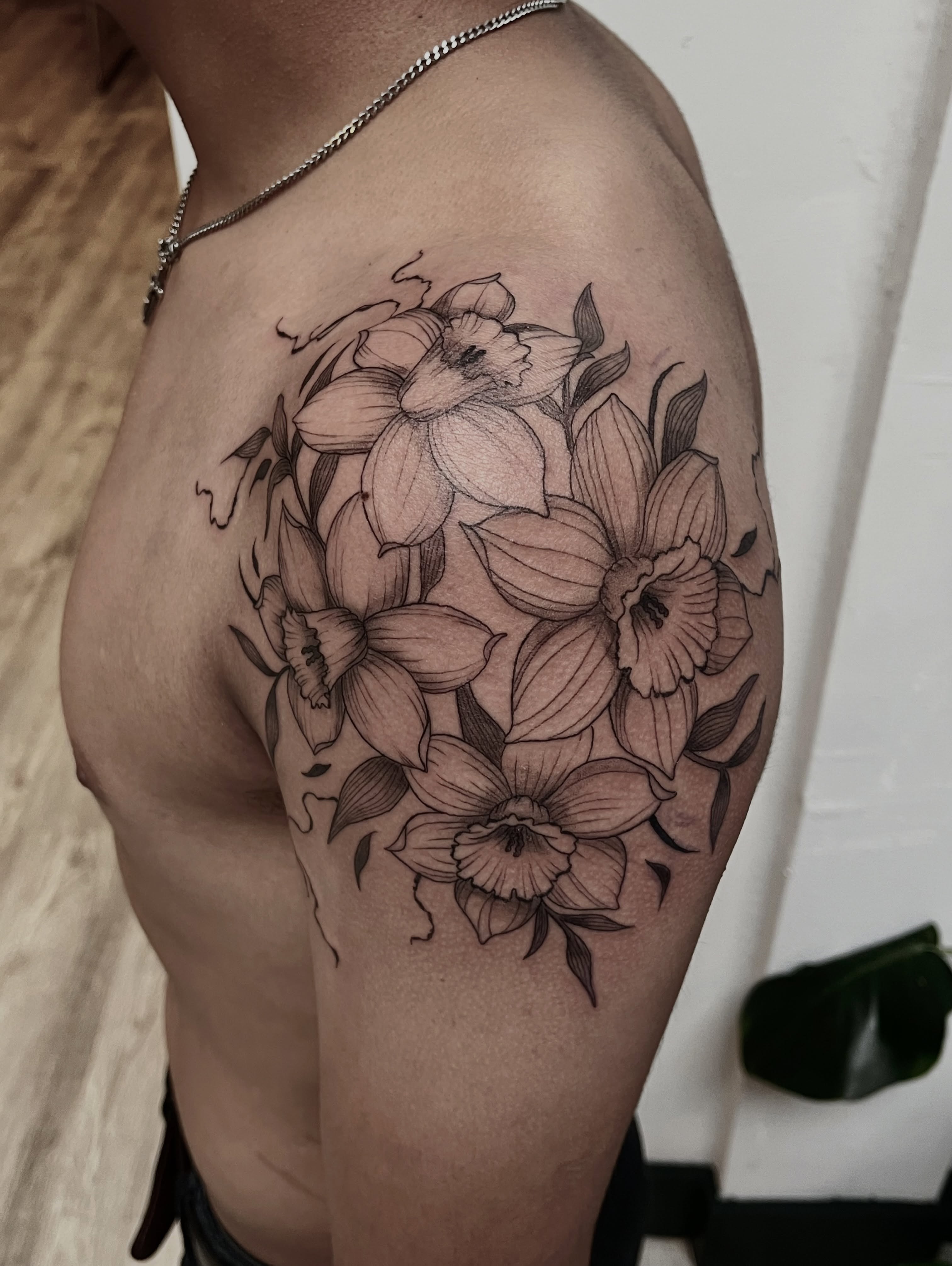 Daffodils black and grey tattoo on the thigh by Lo Gwynn