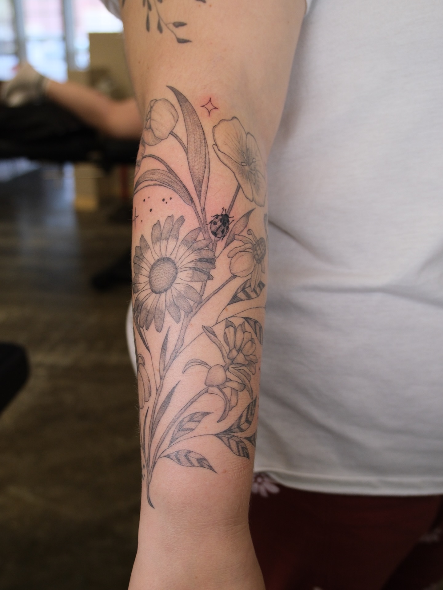 Floral arrangement black and grey tattoo on the forearm by Kiana Hope