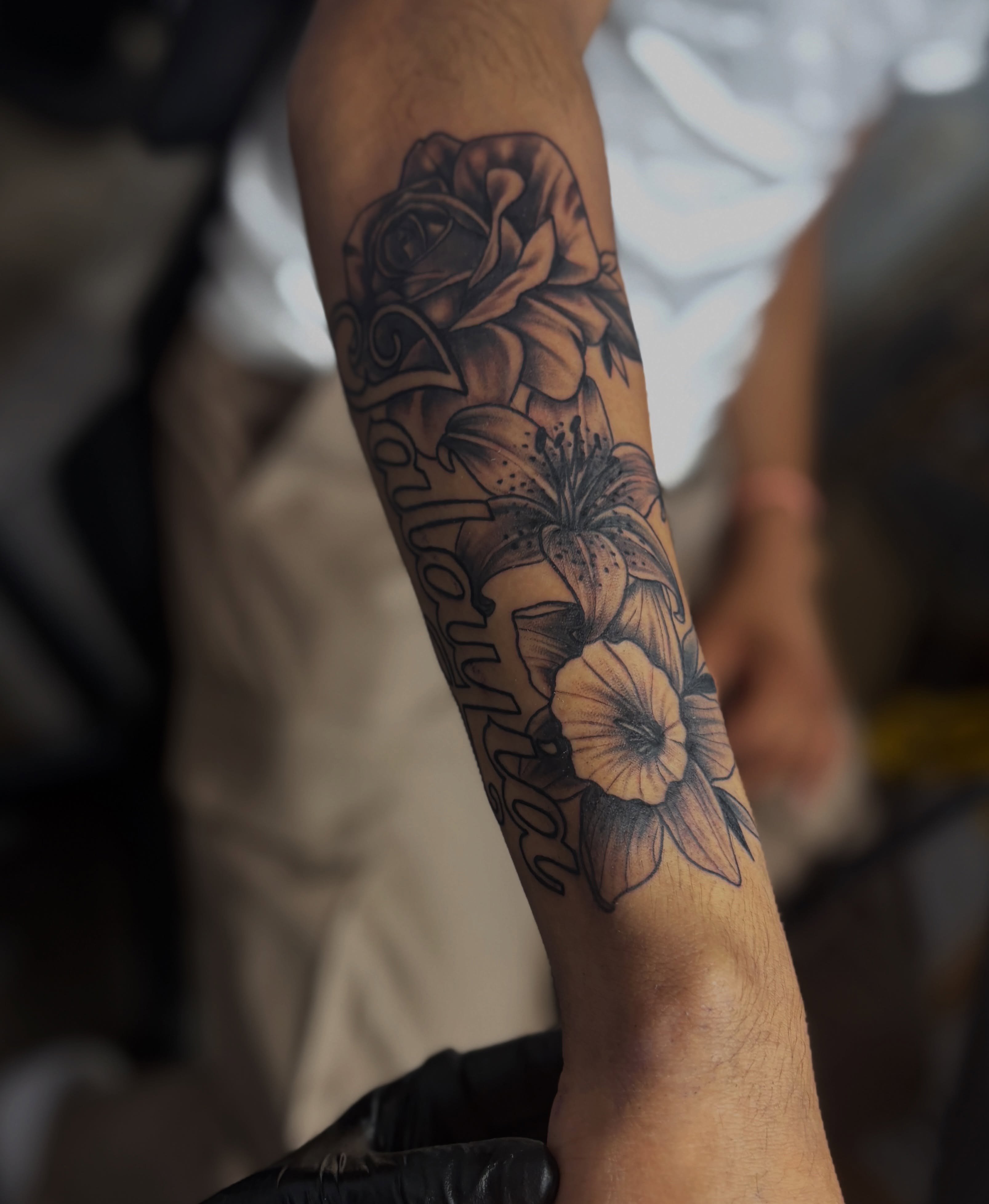 Flowers and script black and grey tattoo on the forearm by Casey - Tattooer, Salem, Massachusetts