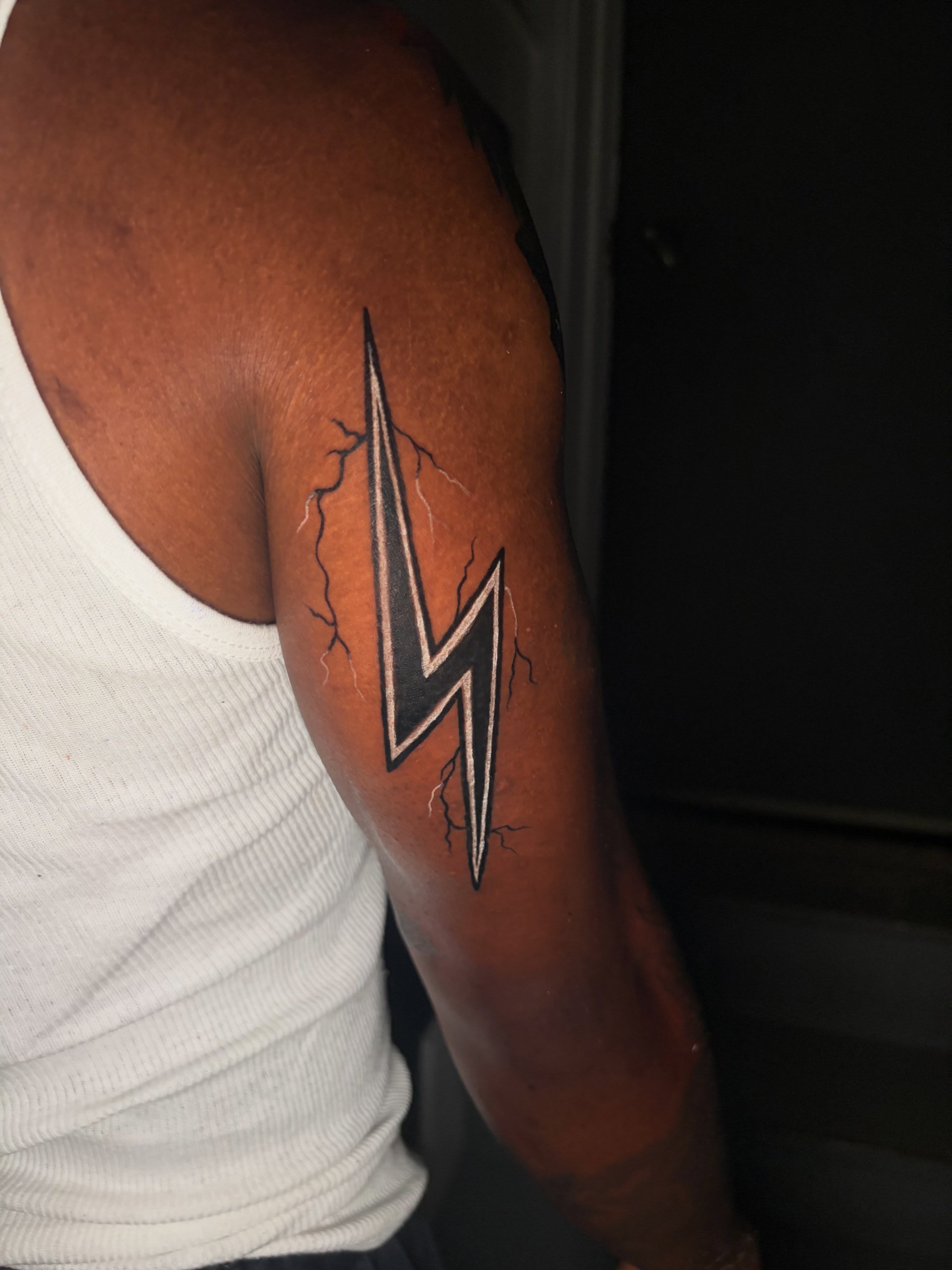 Lightning bolt geometric tattoo on the upper arm by @getmoneetattz