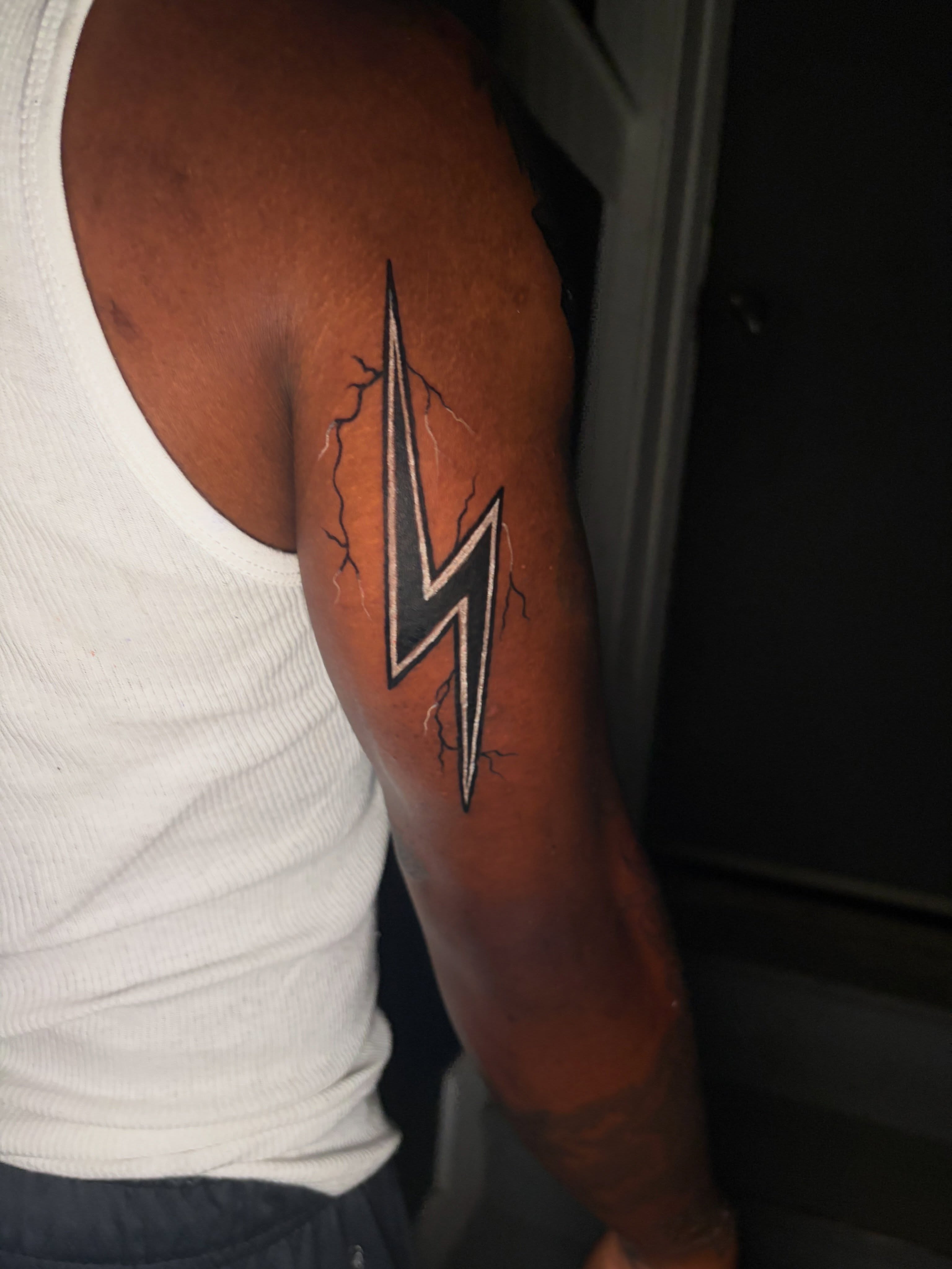Lightning bolt geometric tattoo on the upper arm by @getmoneetattz