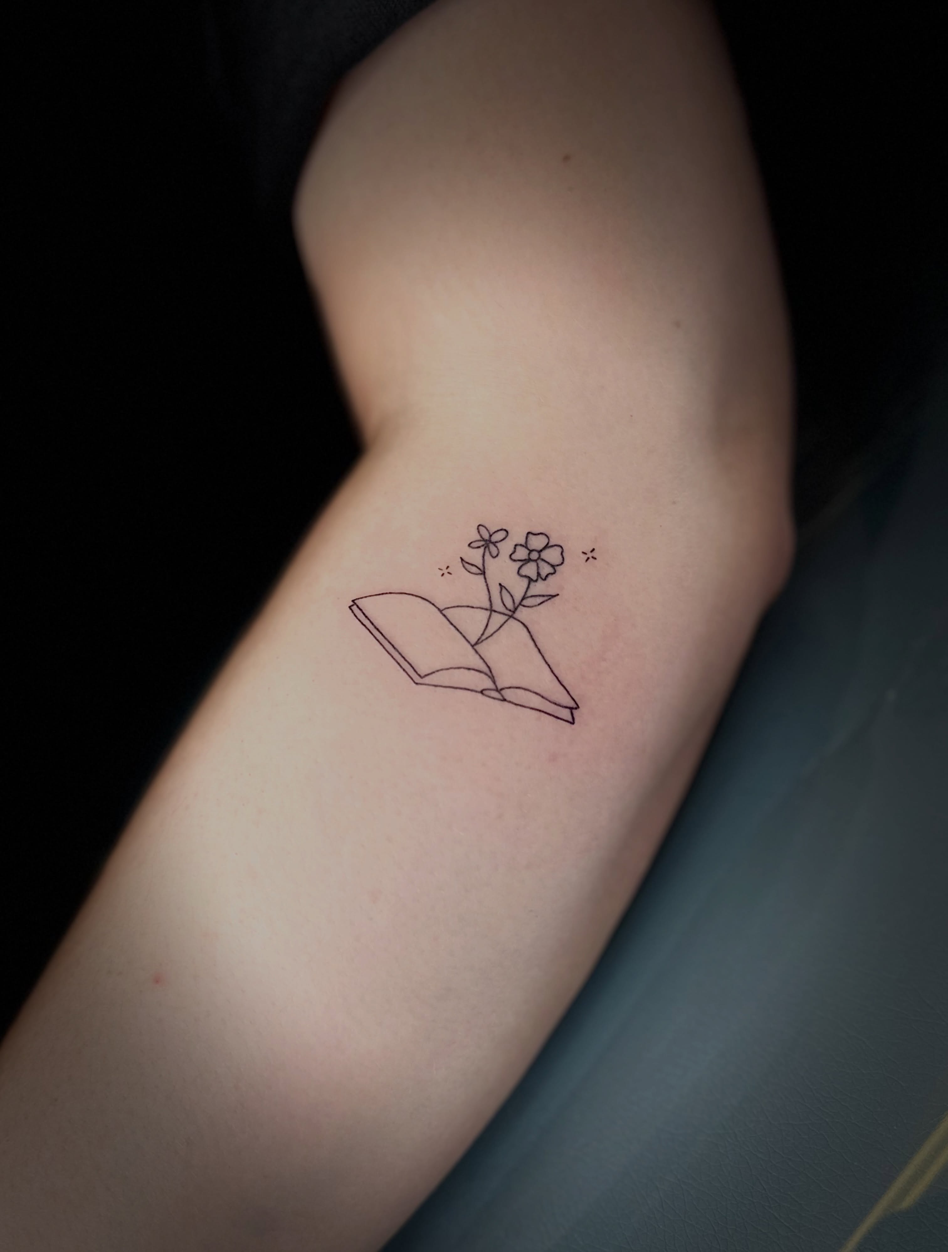 Book and flowers fine line tattoo on the forearm by NuNu