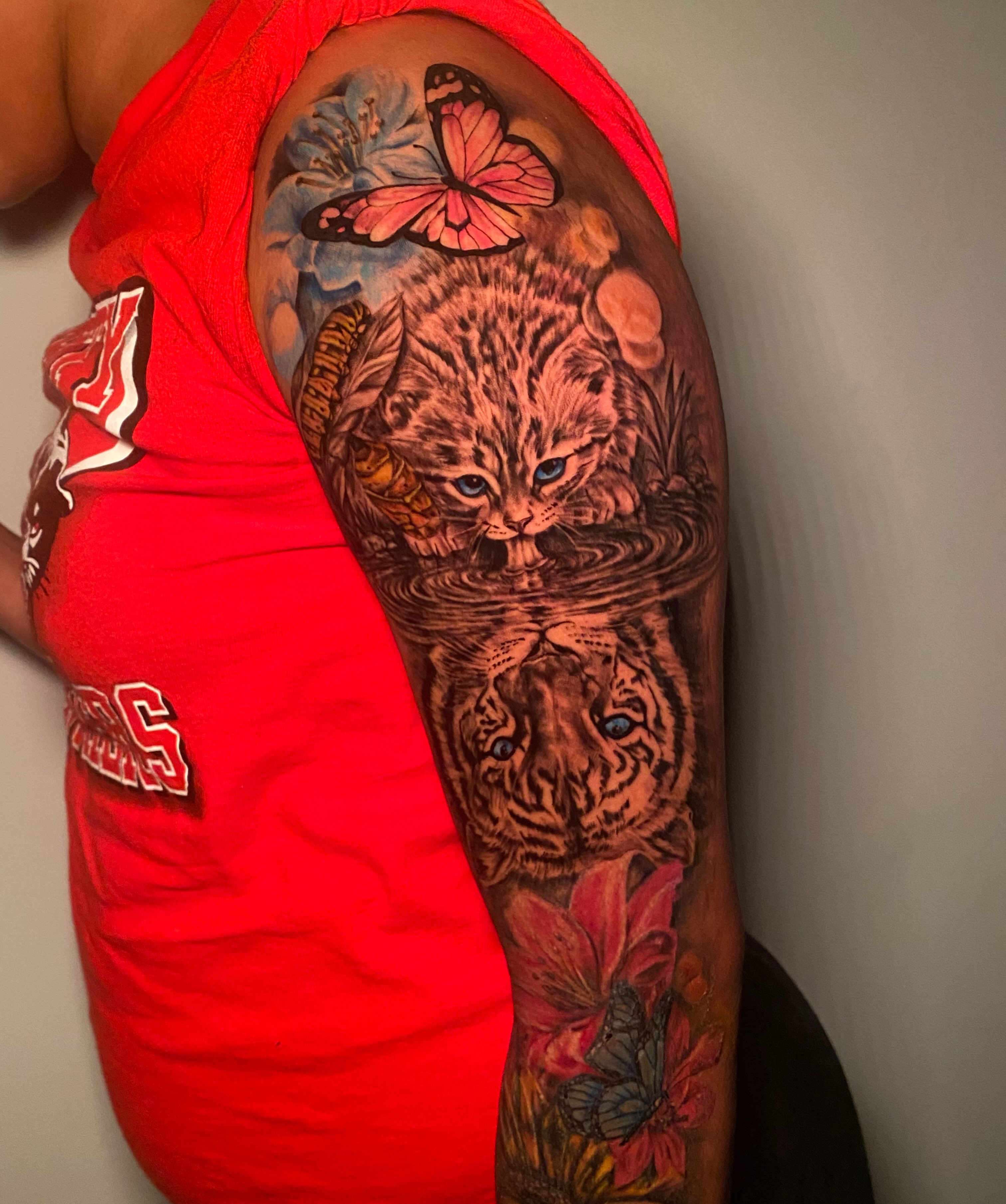 Cat and tiger reflection realism tattoo on the upper arm by Tattoo Artist