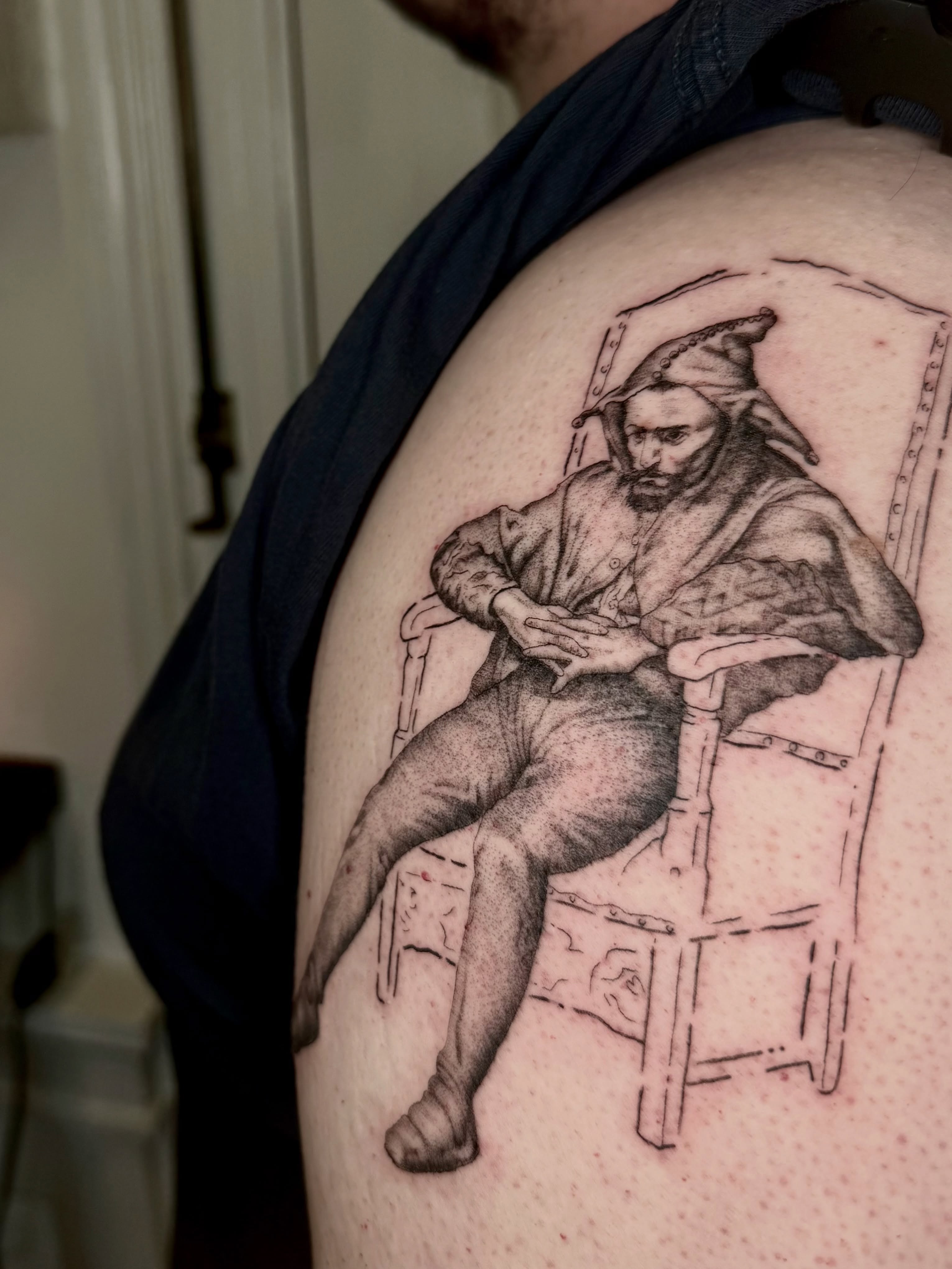 Man sitting black and grey tattoo on the shoulder by Ian Saner