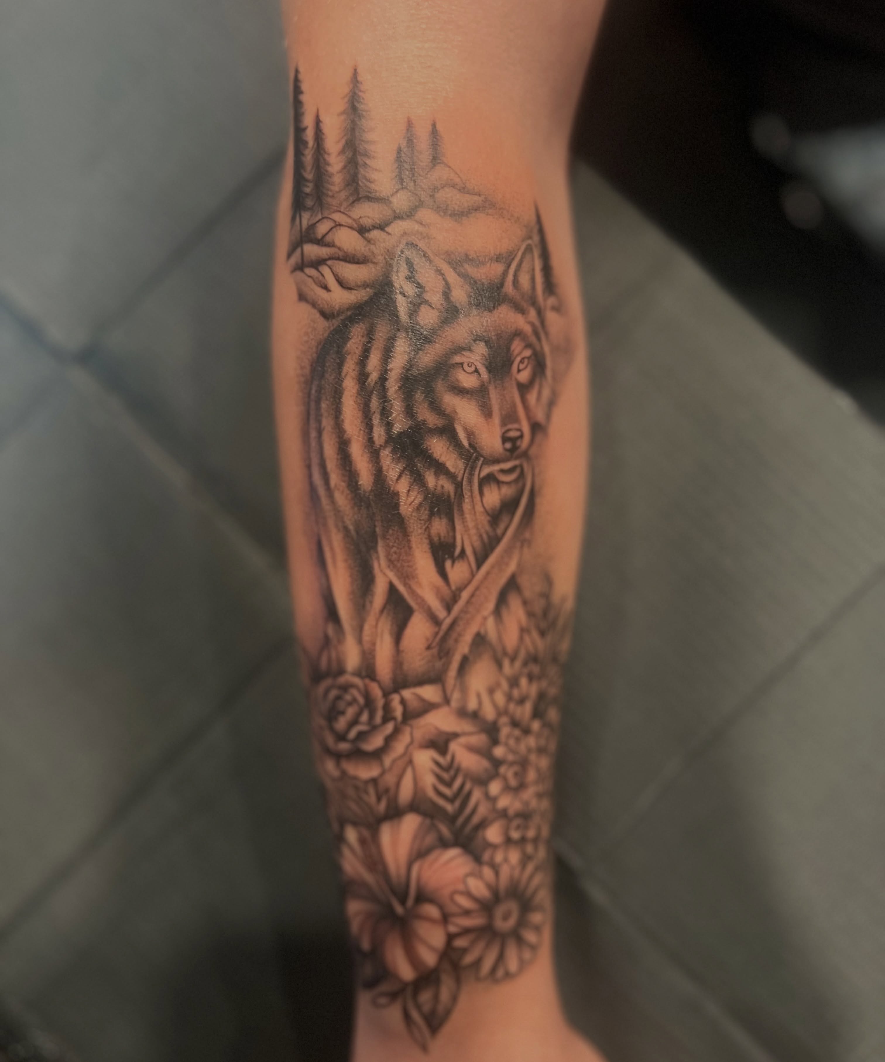 Wolf and flowers realism tattoo on the forearm by Jai Woods