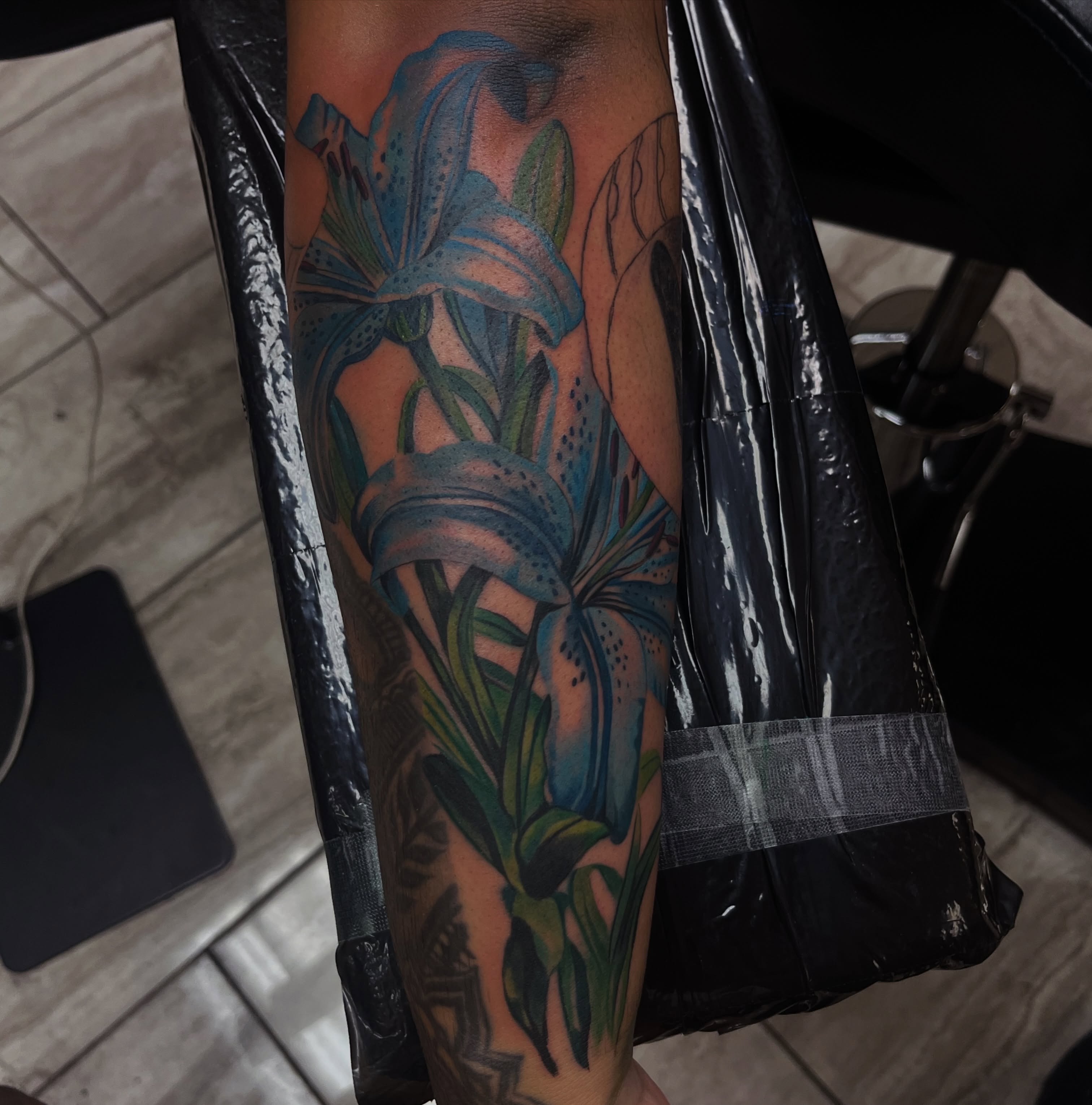 Lilies realism tattoo on the forearm by Quinten Harper