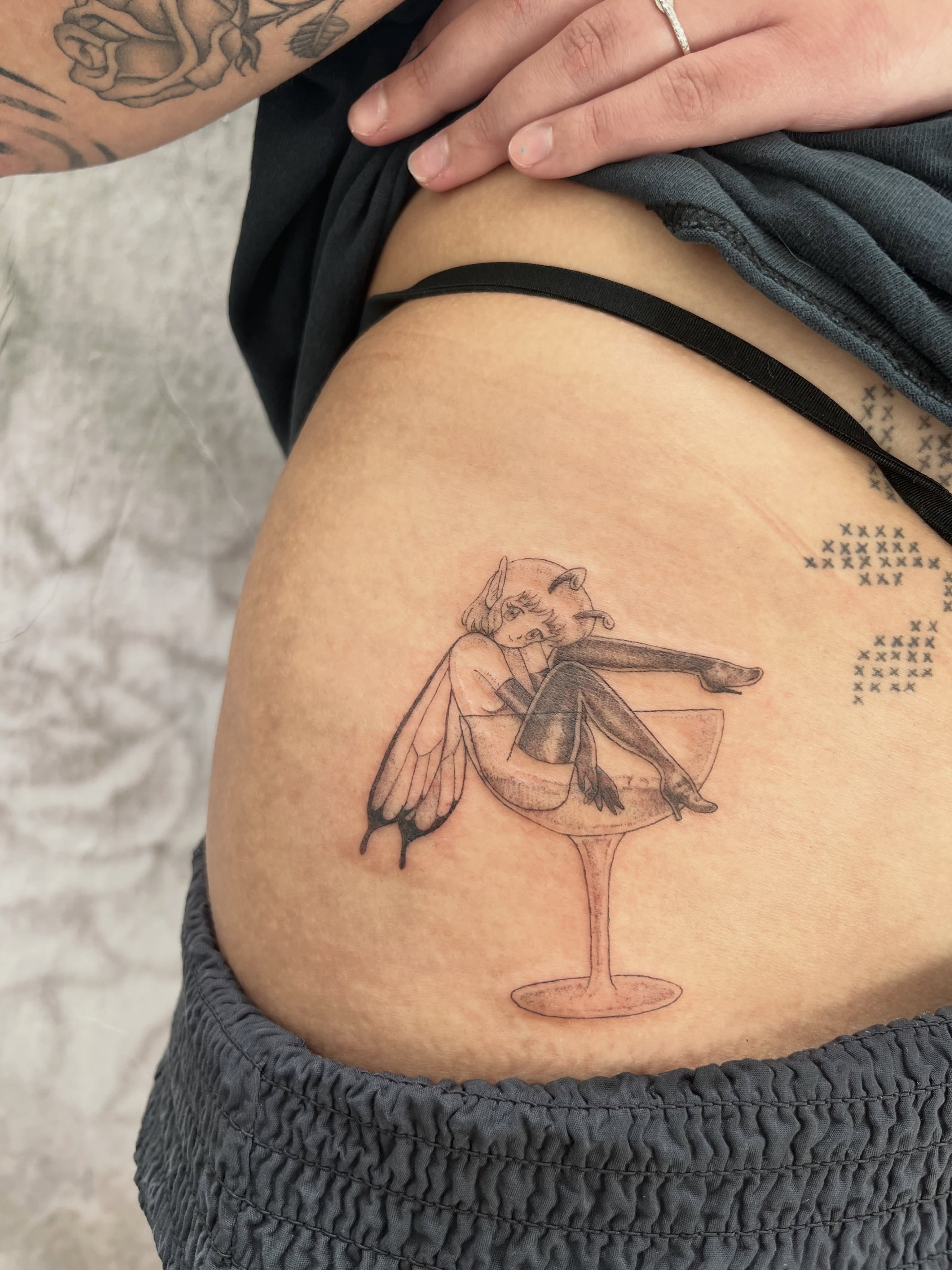 Angel in cocktail glass black and grey tattoo on the thigh by Kyra Monterrosa
