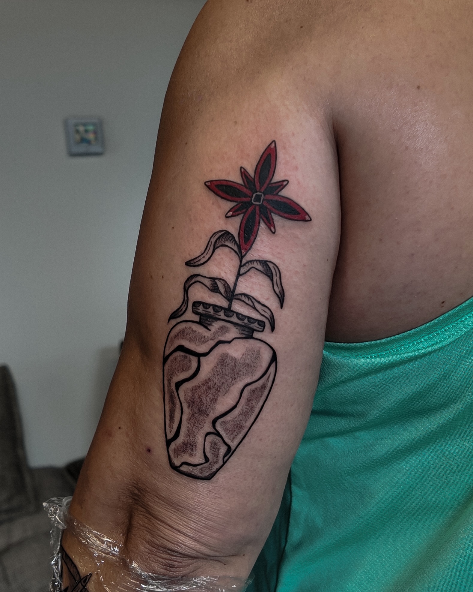 Heart with plant black and grey tattoo on the upper arm by Morgan Diann