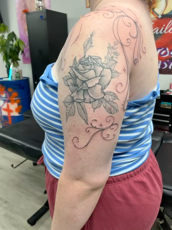 Rose black and grey tattoo on the upper arm by Tattoos by Hailey