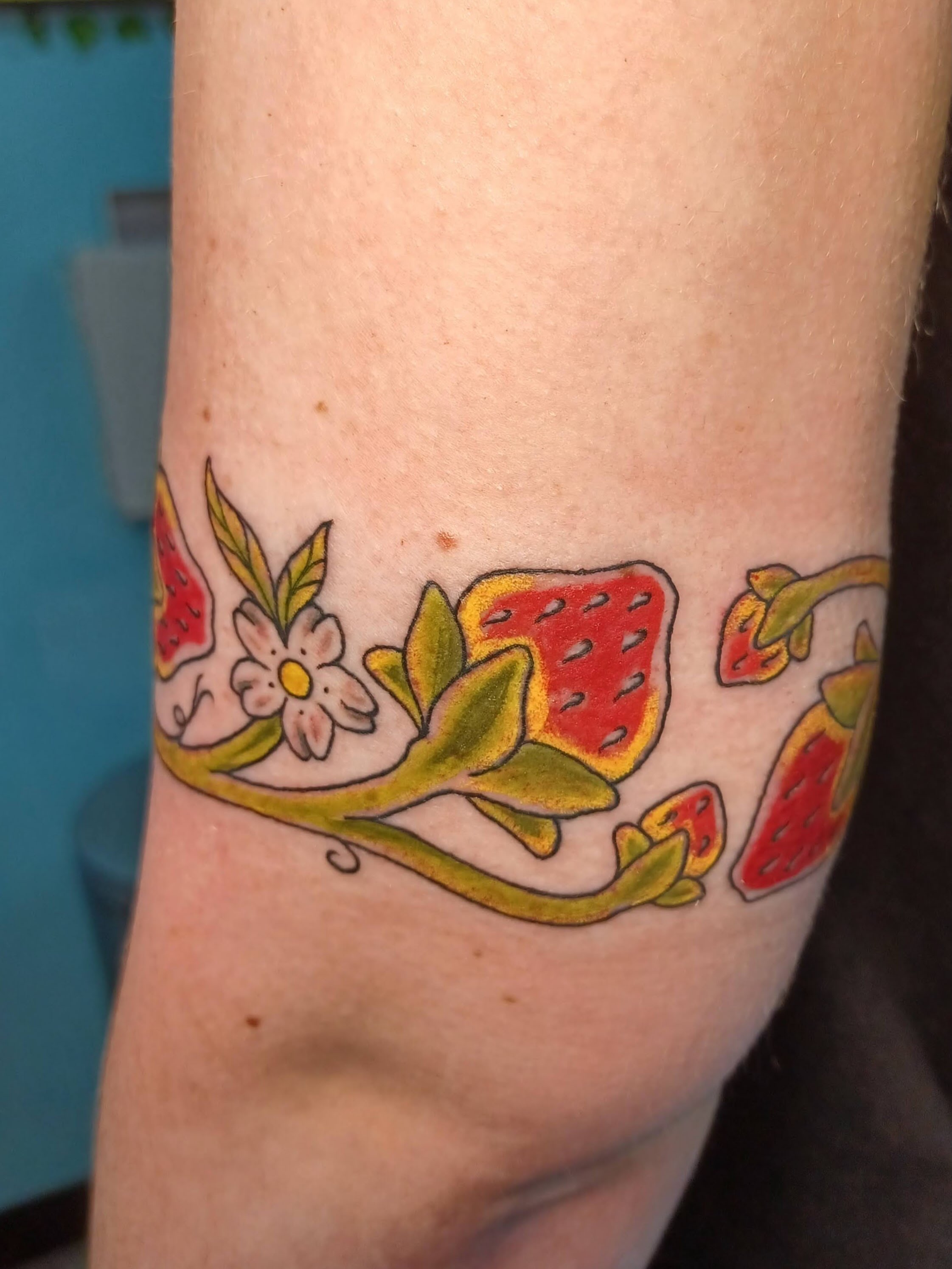 Strawberries and flowers new school tattoo on the forearm by Abi