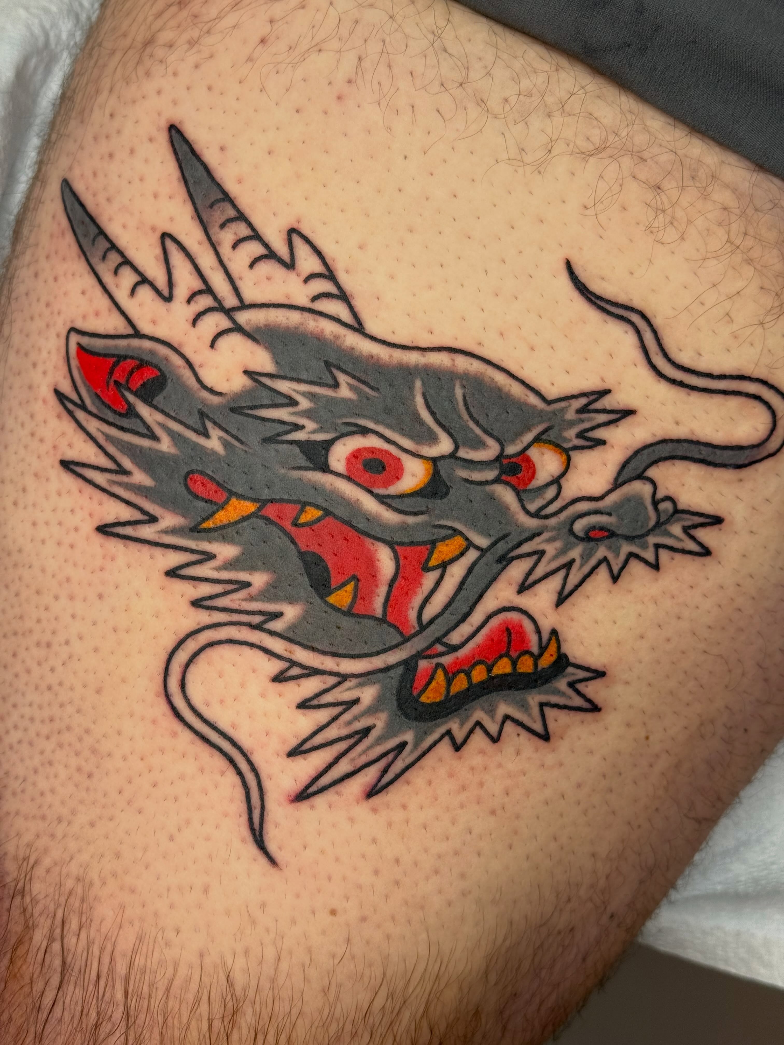 Dragon head American traditional tattoo on the thigh by Emma Eaton