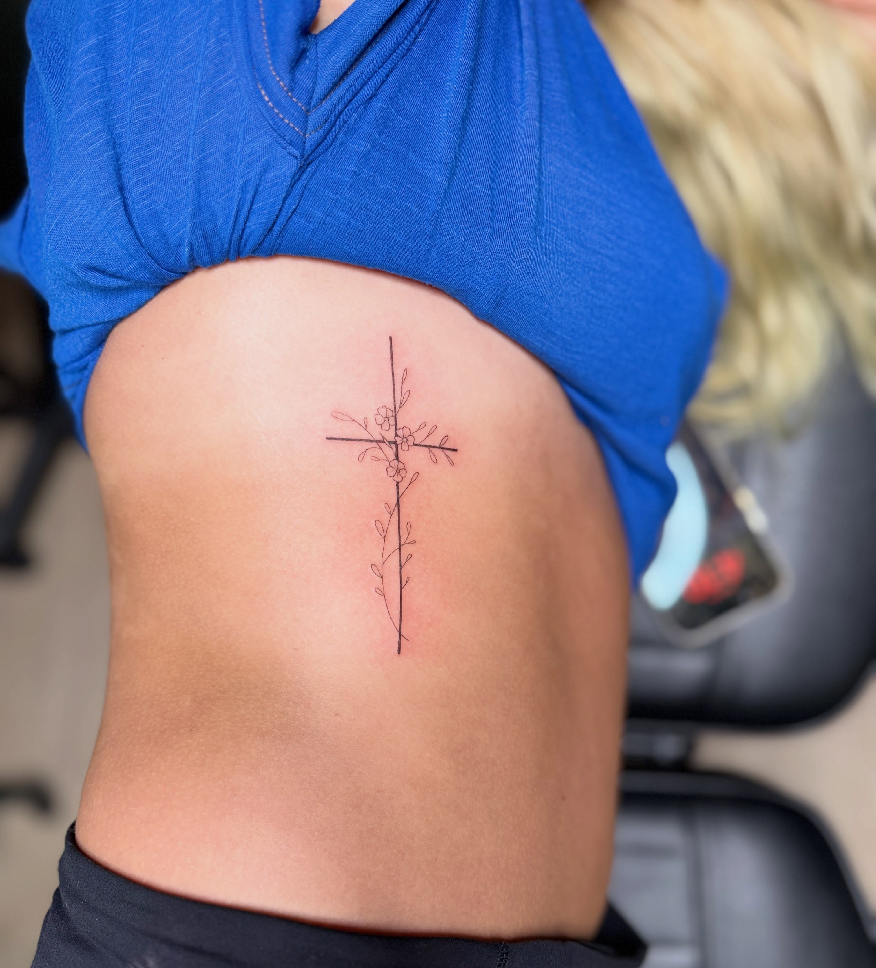 Cross with floral details fine line tattoo on the ribs by Fineline Tattoos π€ Hailey L.
