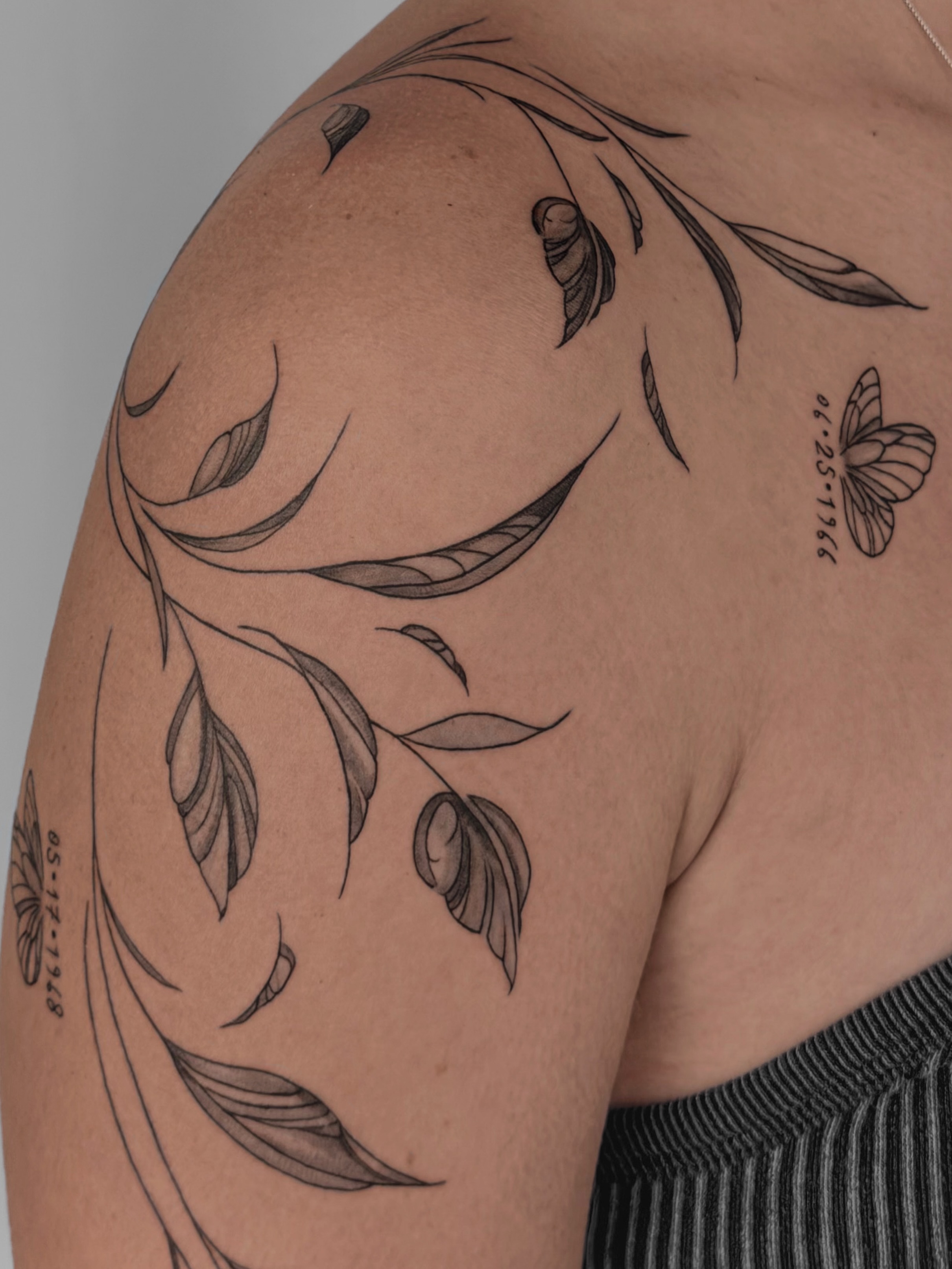 Branch with leaves black and grey tattoo on the shoulder by Charlotte