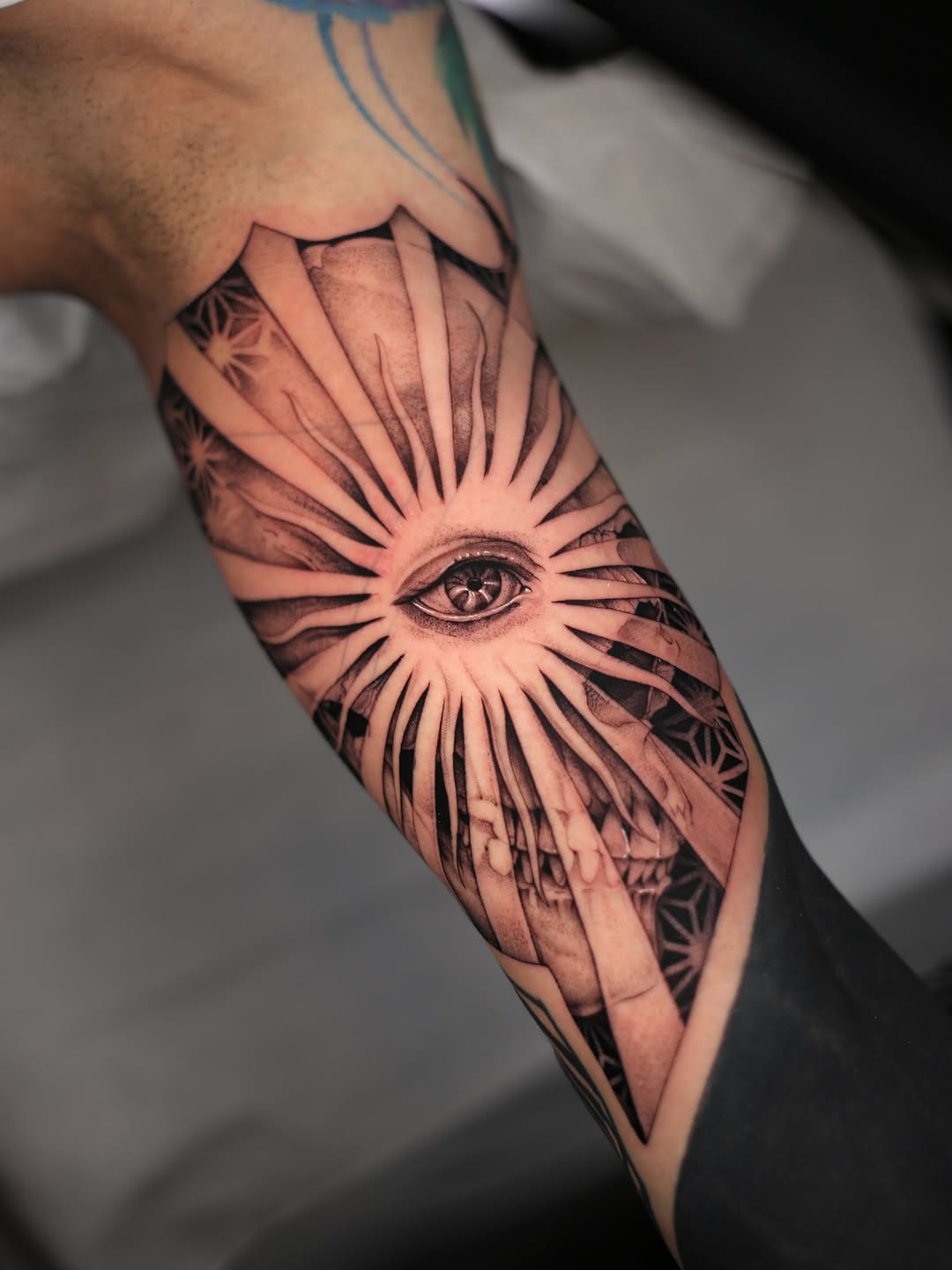 Eye and skull with sun rays geometric tattoo on the forearm by Steve Franciosa