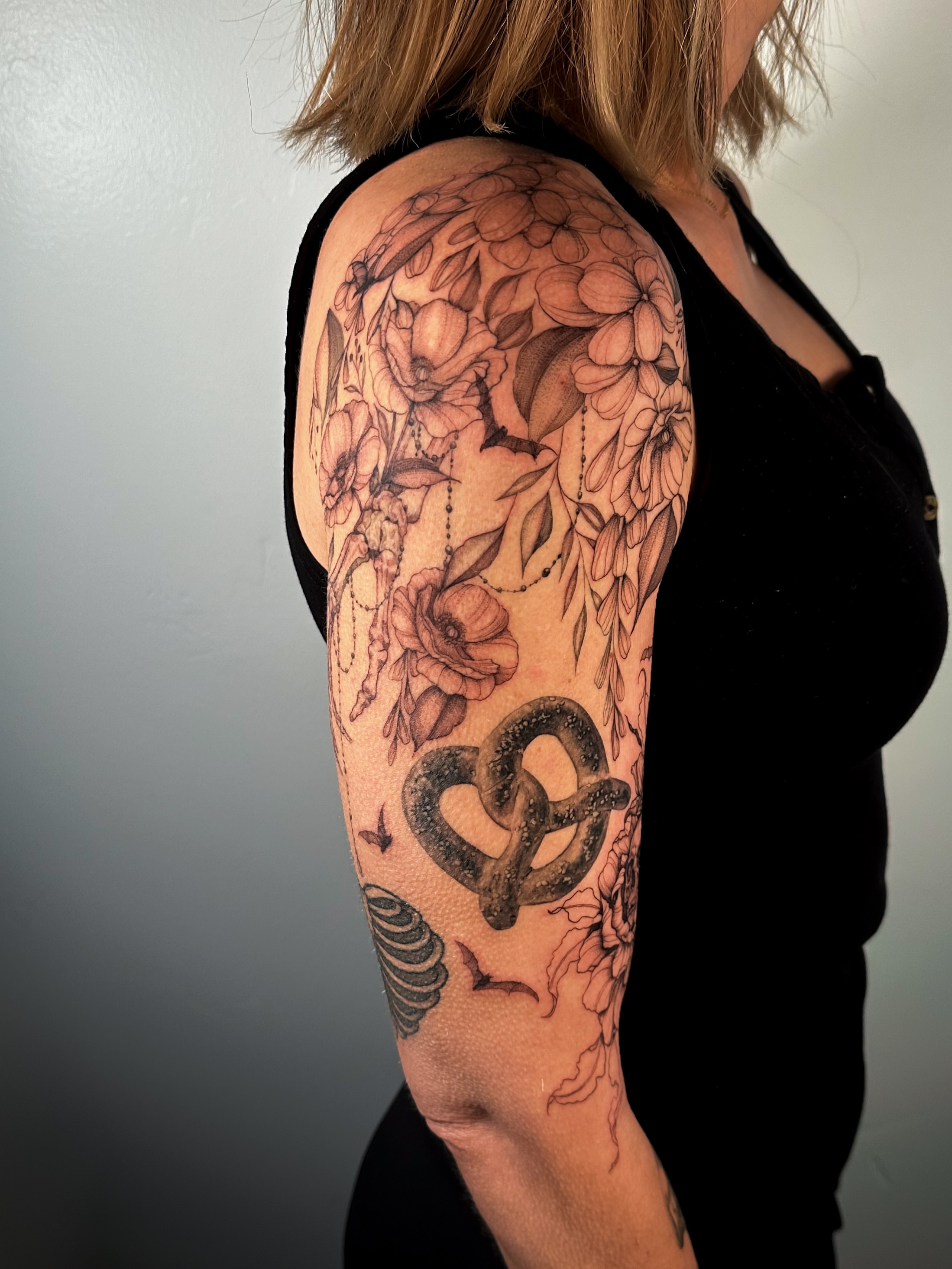 Pretzel and floral realism tattoo on the forearm by Caroline + Utah Tattoo Artist