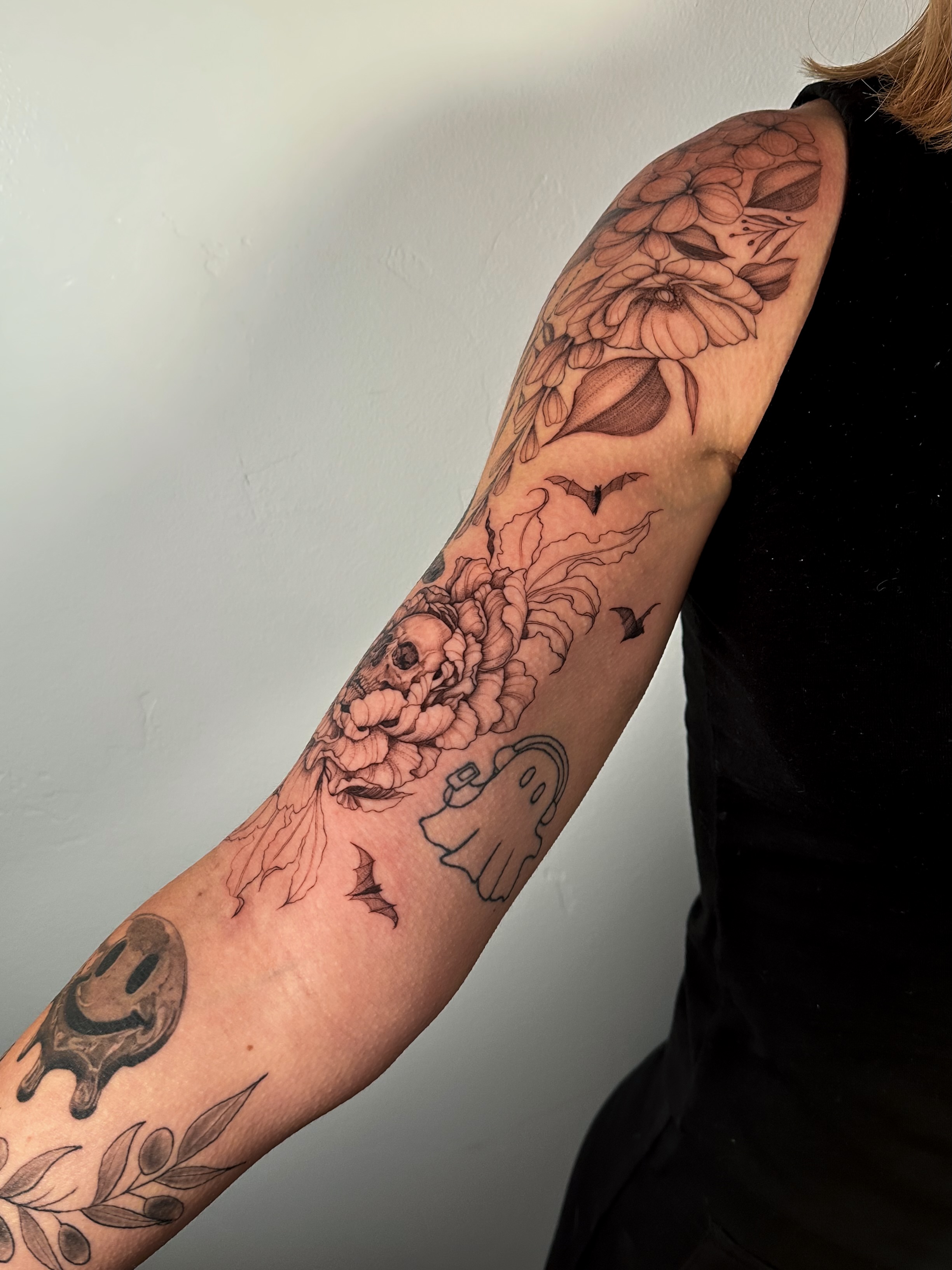 Floral and ghost black and grey tattoo on the forearm by Caroline + Utah Tattoo Artist