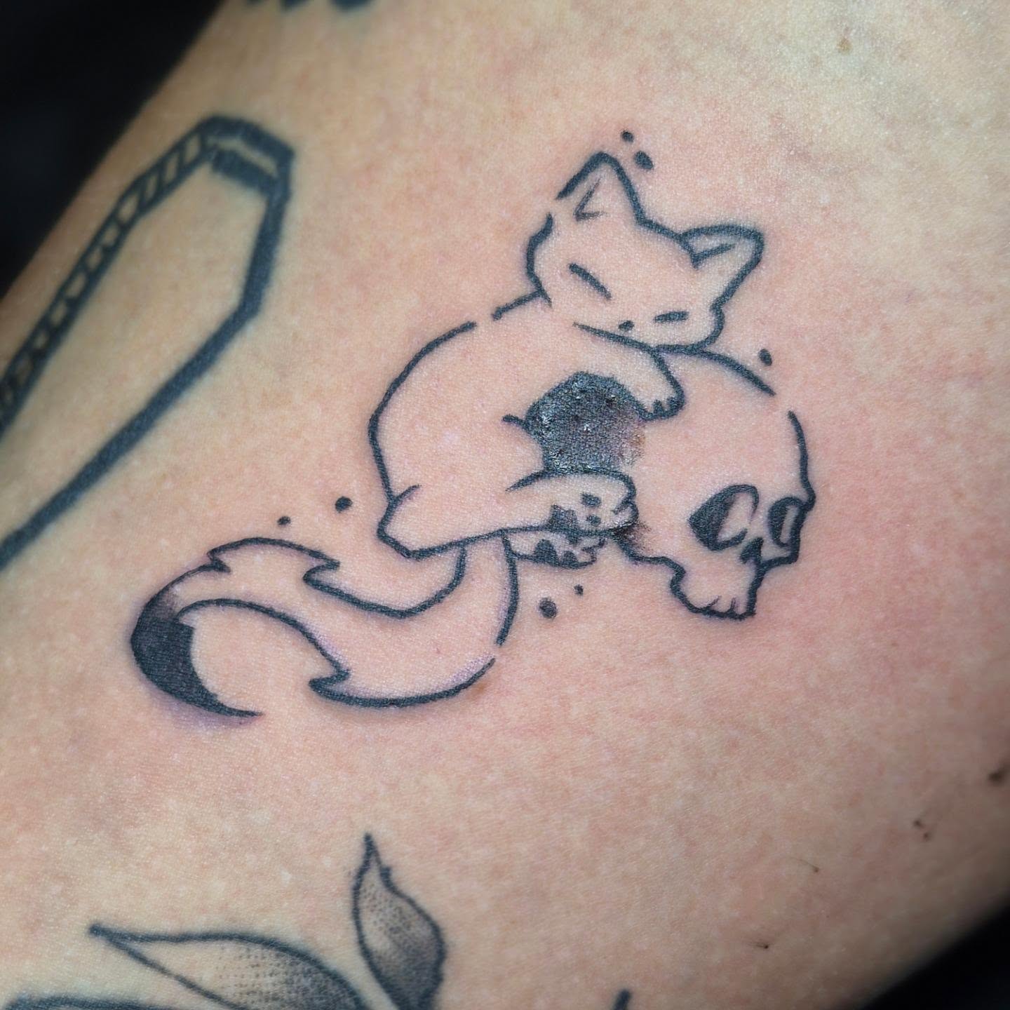 Cat and skull dotwork tattoo on the upper arm by Bobby H