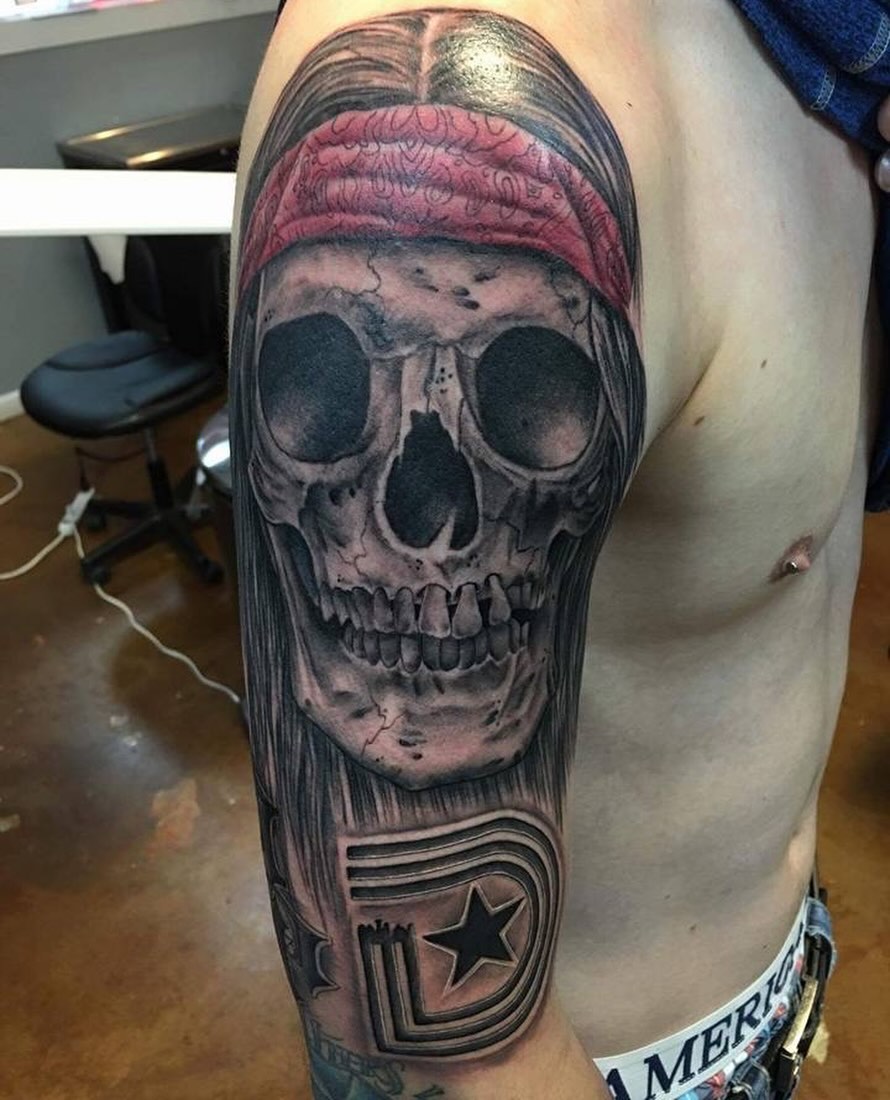 Skull with bandana realism tattoo on the upper arm by Cuda