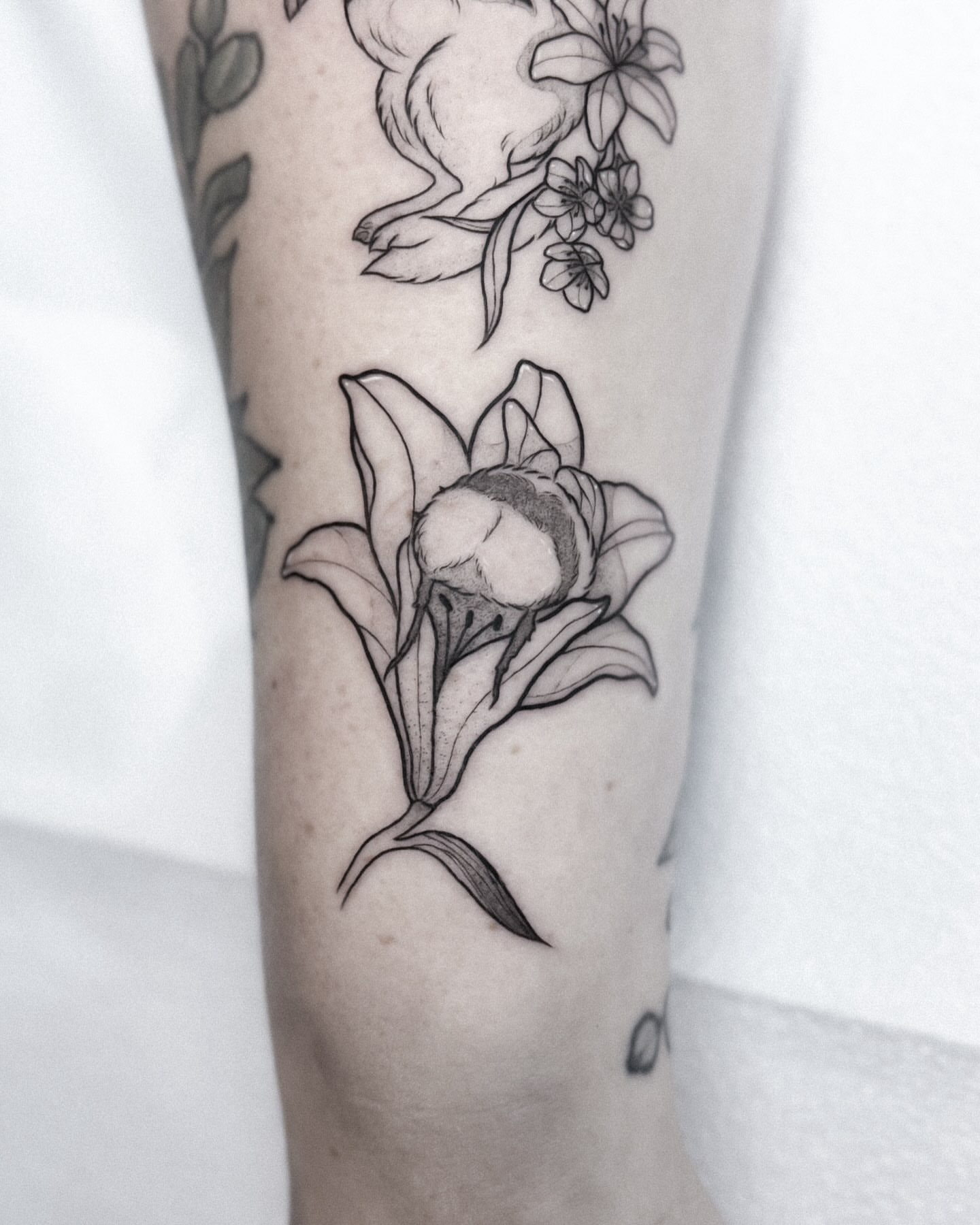 Lily black and grey tattoo on the forearm by Whimsical Tattoos