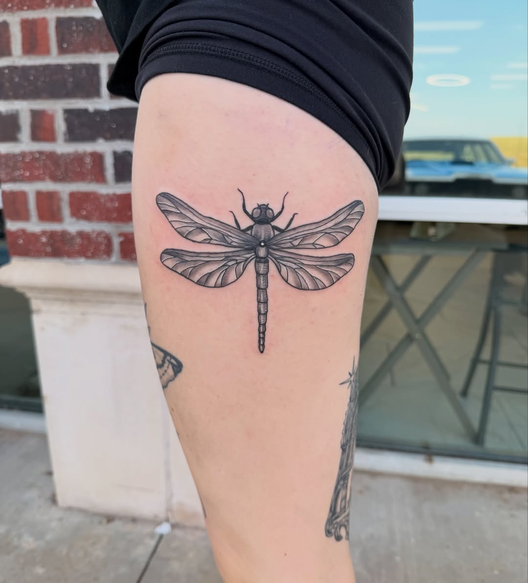 Dragonfly black and grey tattoo on the thigh by Lexi Odam
