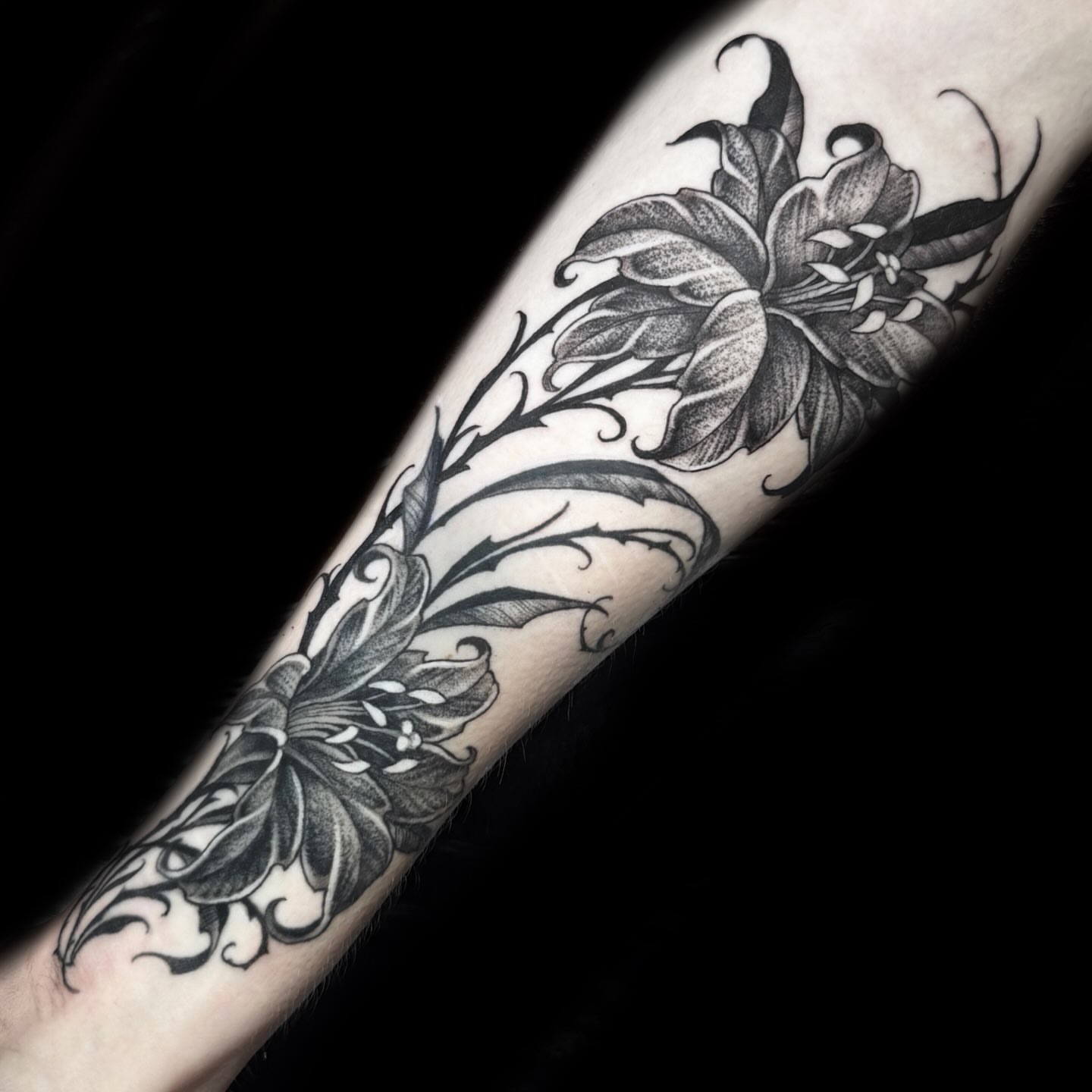 Lilies black and grey tattoo on the forearm by Kelsea Weir McCree