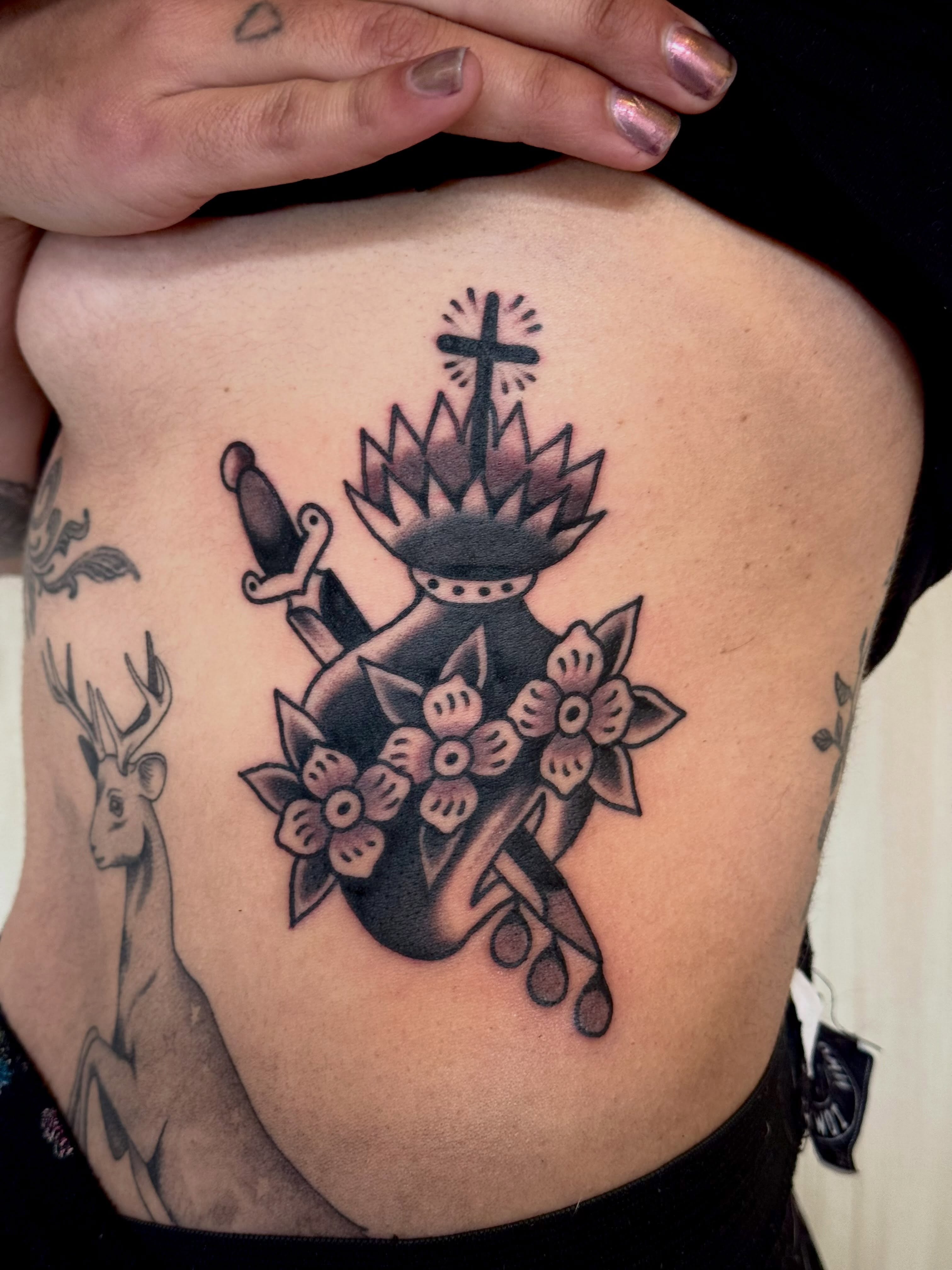 Heart with crown and dagger American traditional tattoo on the ribs by Eli Bernal