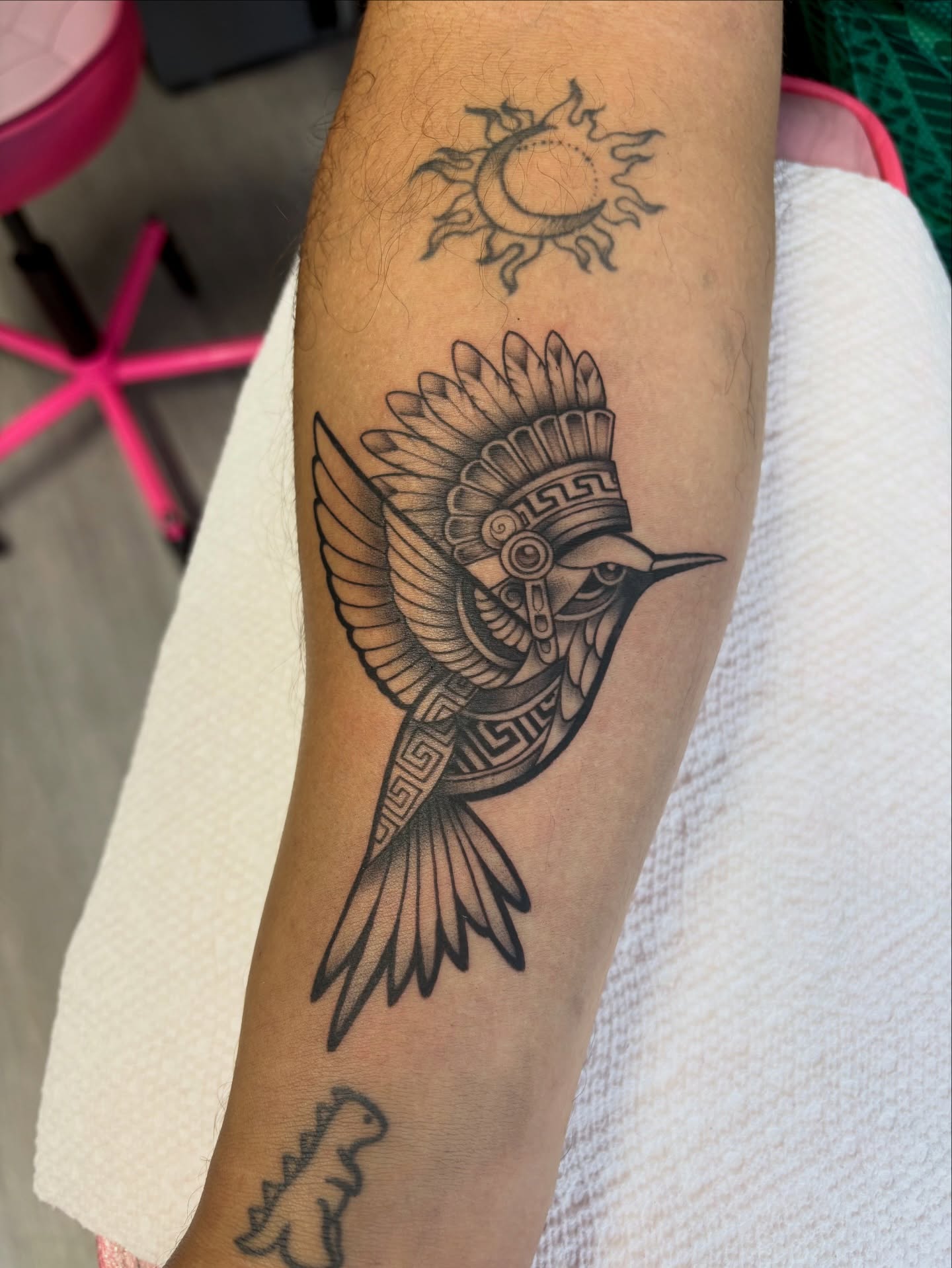 Bird wearing headdress black and grey tattoo on the forearm by Elixabeth