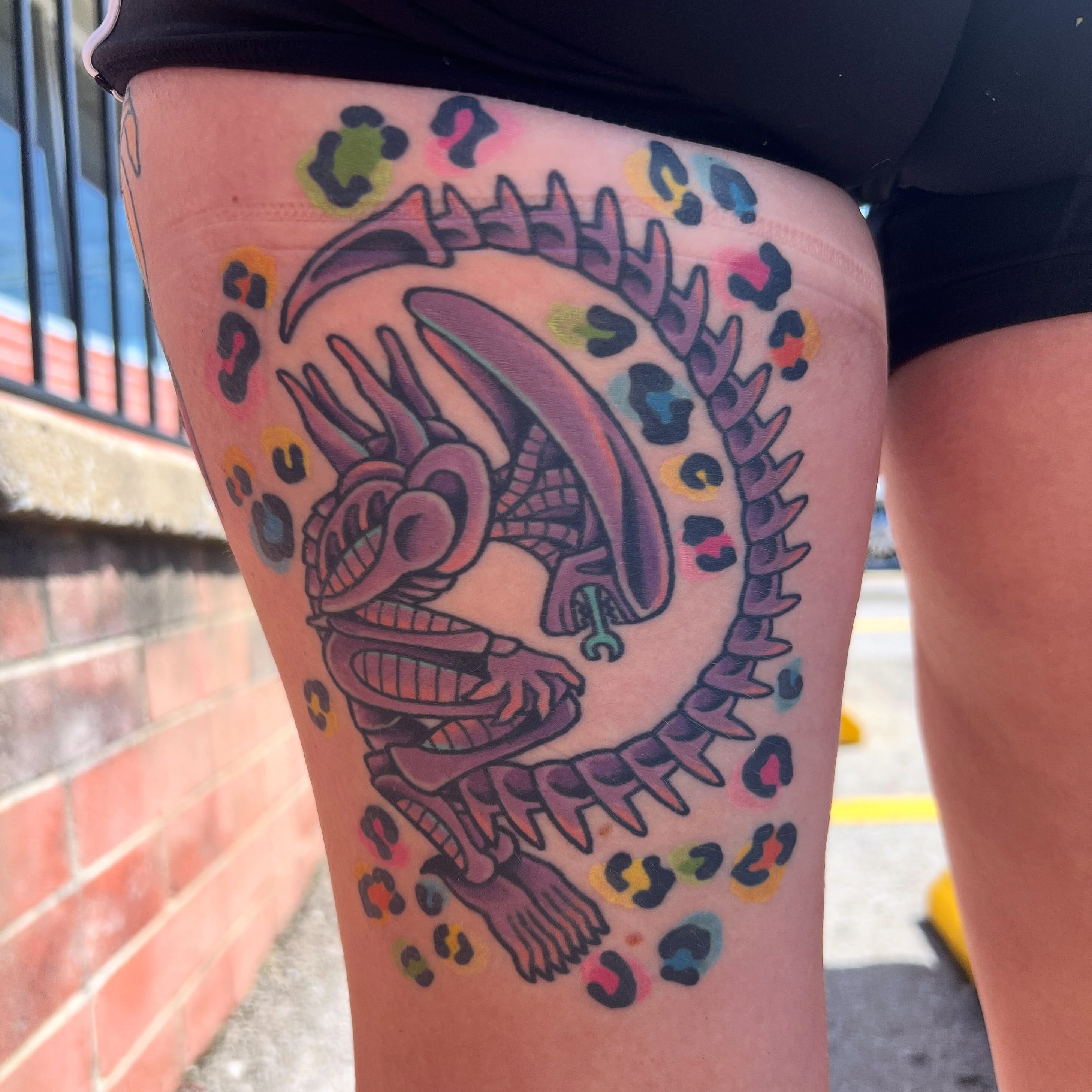 Alien head trash polka tattoo on the thigh by Taylor Estrella