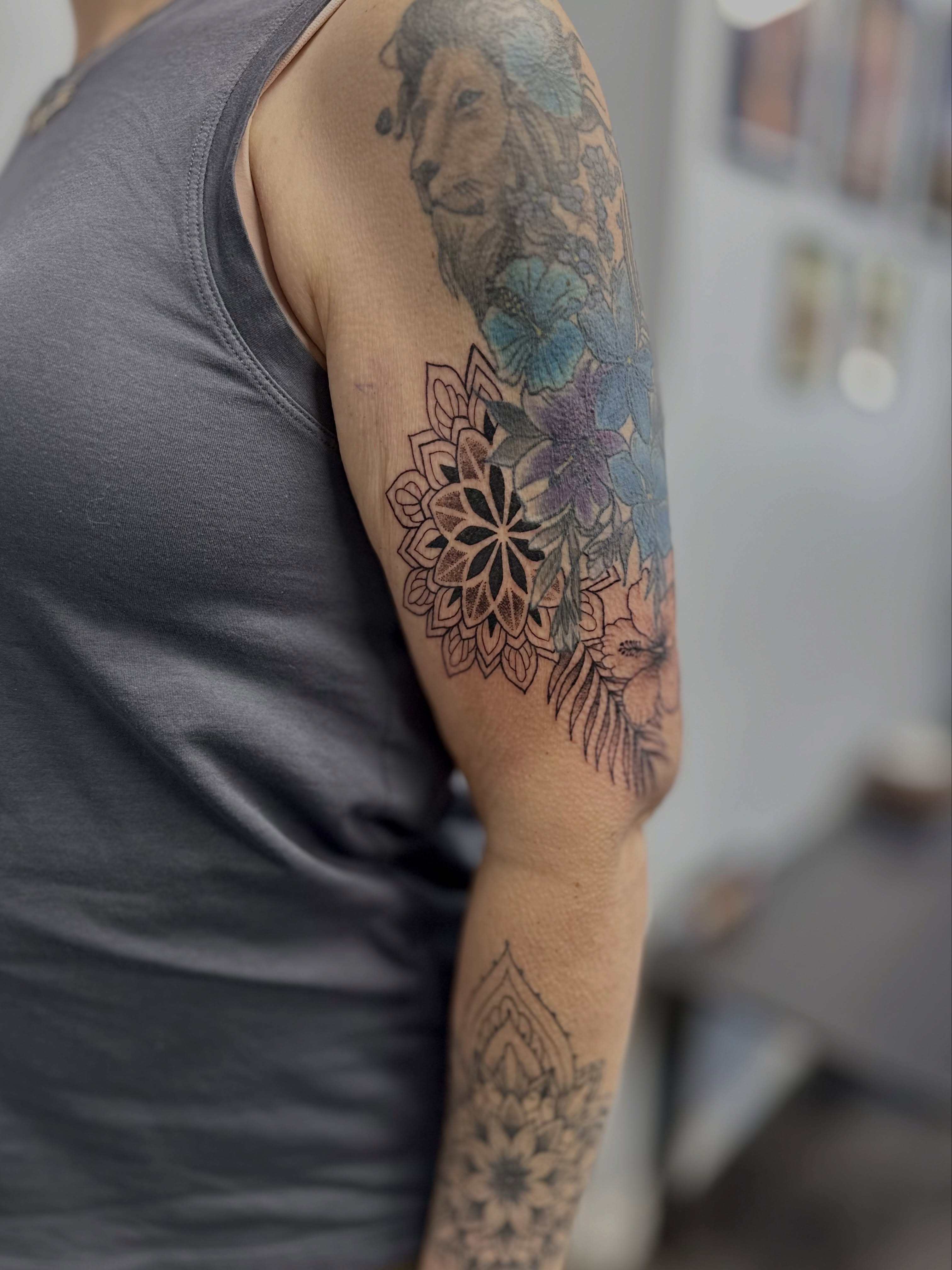 Mandala and lion geometric tattoo on the upper arm by AJ