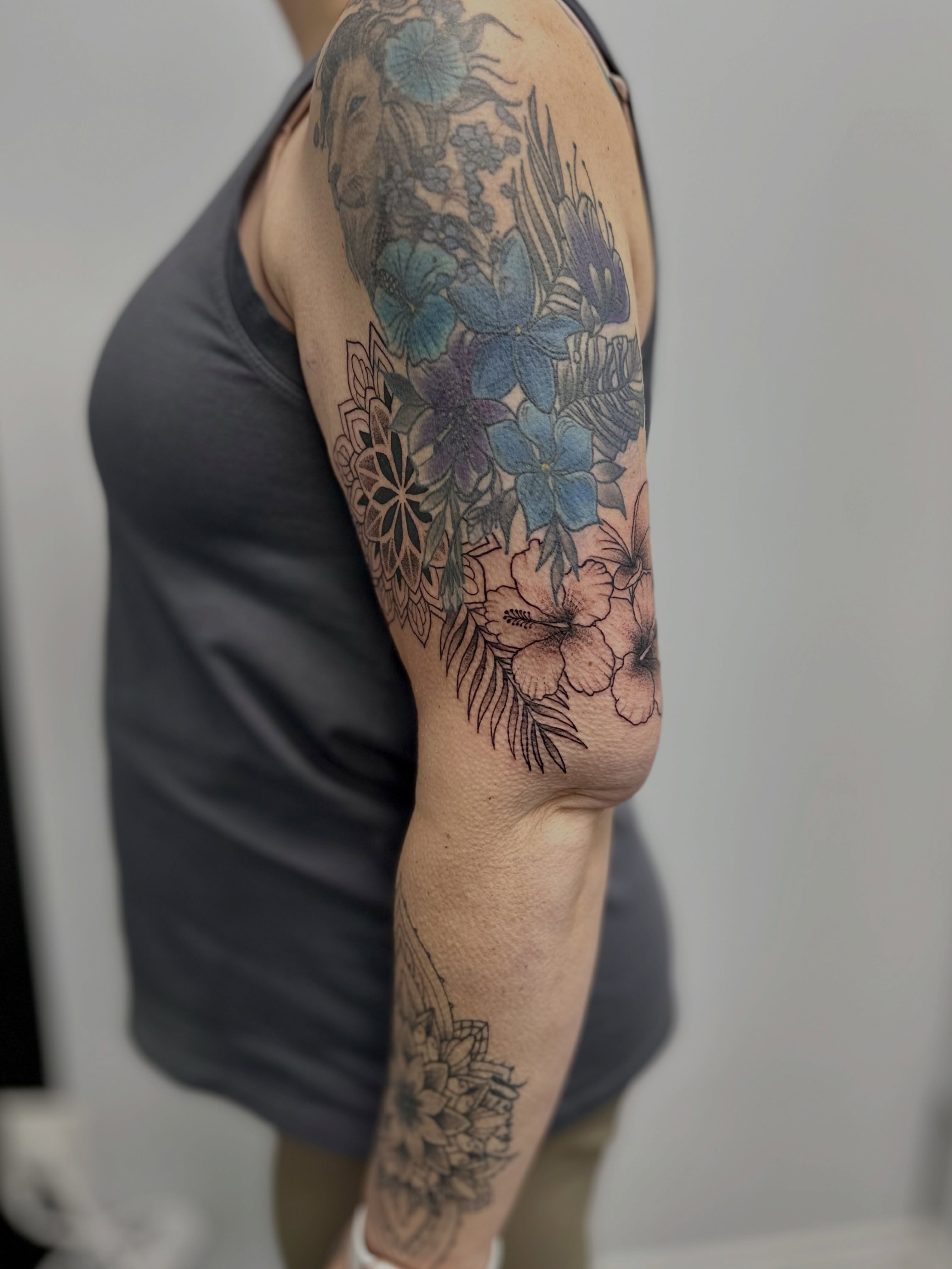 Floral arrangement dotwork tattoo on the upper arm by AJ