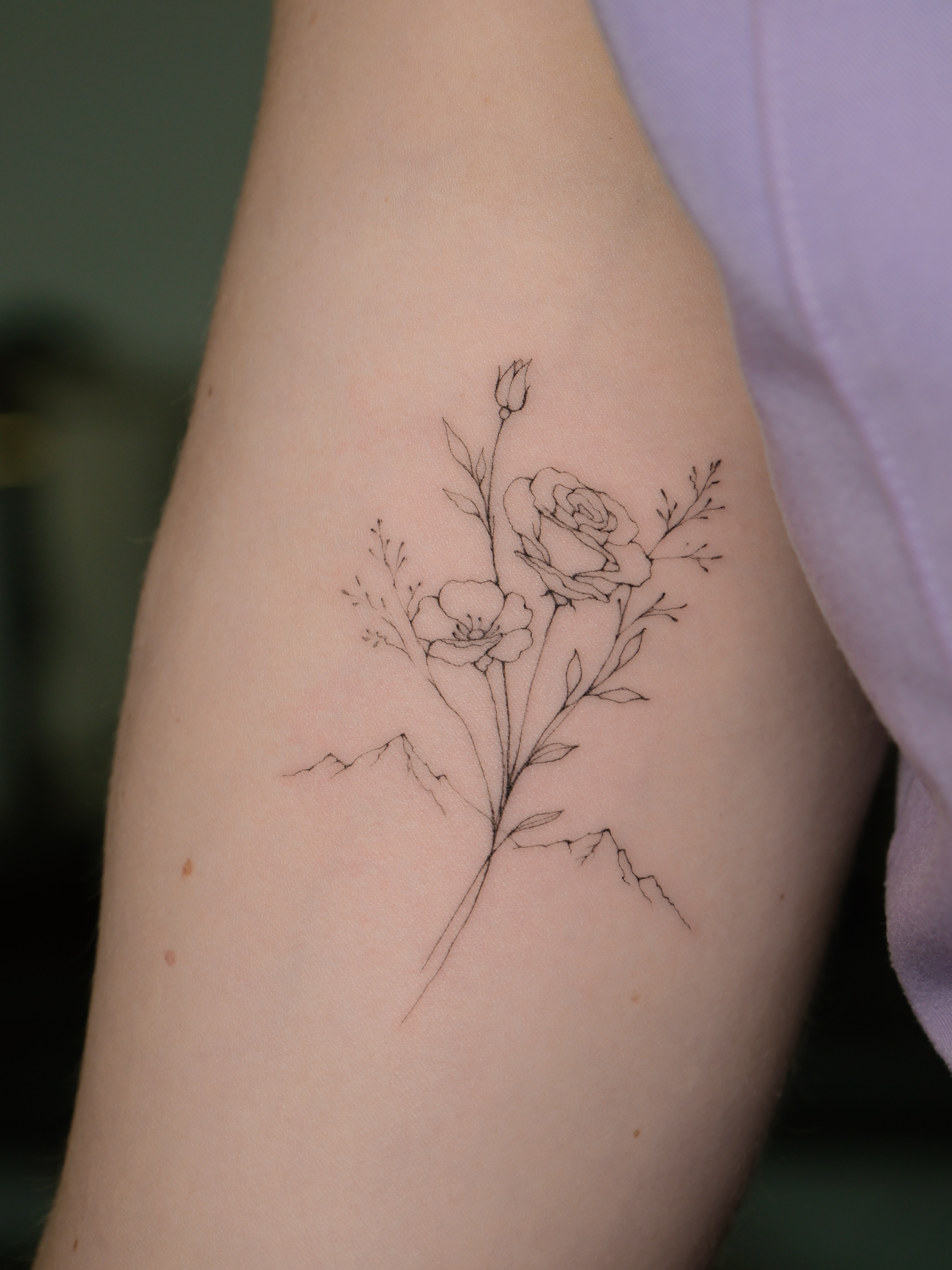Floral bouquet fine line tattoo on the forearm by Victoria