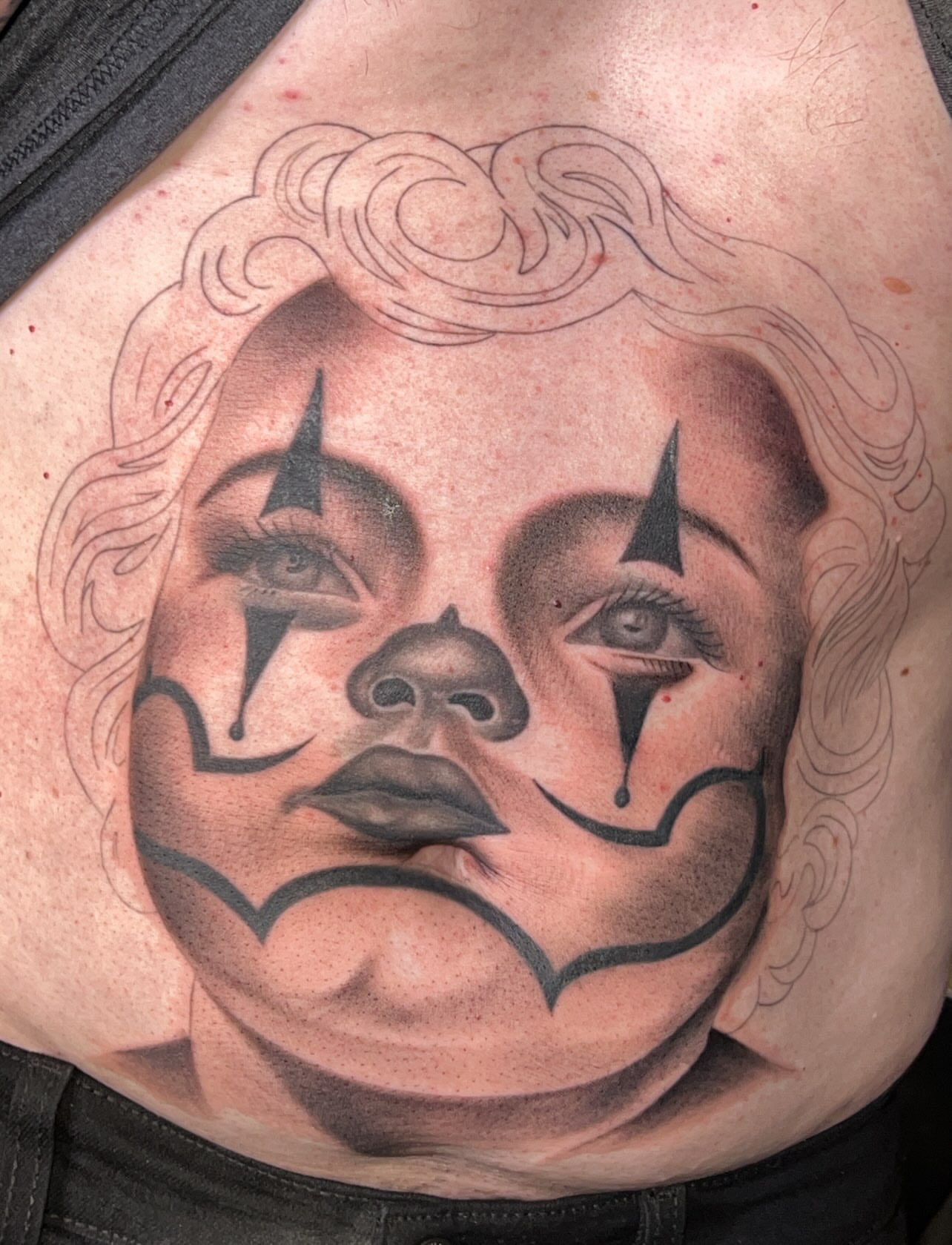 Clown face black and grey tattoo on the chest by Dallas tx tattoo artist ✝️