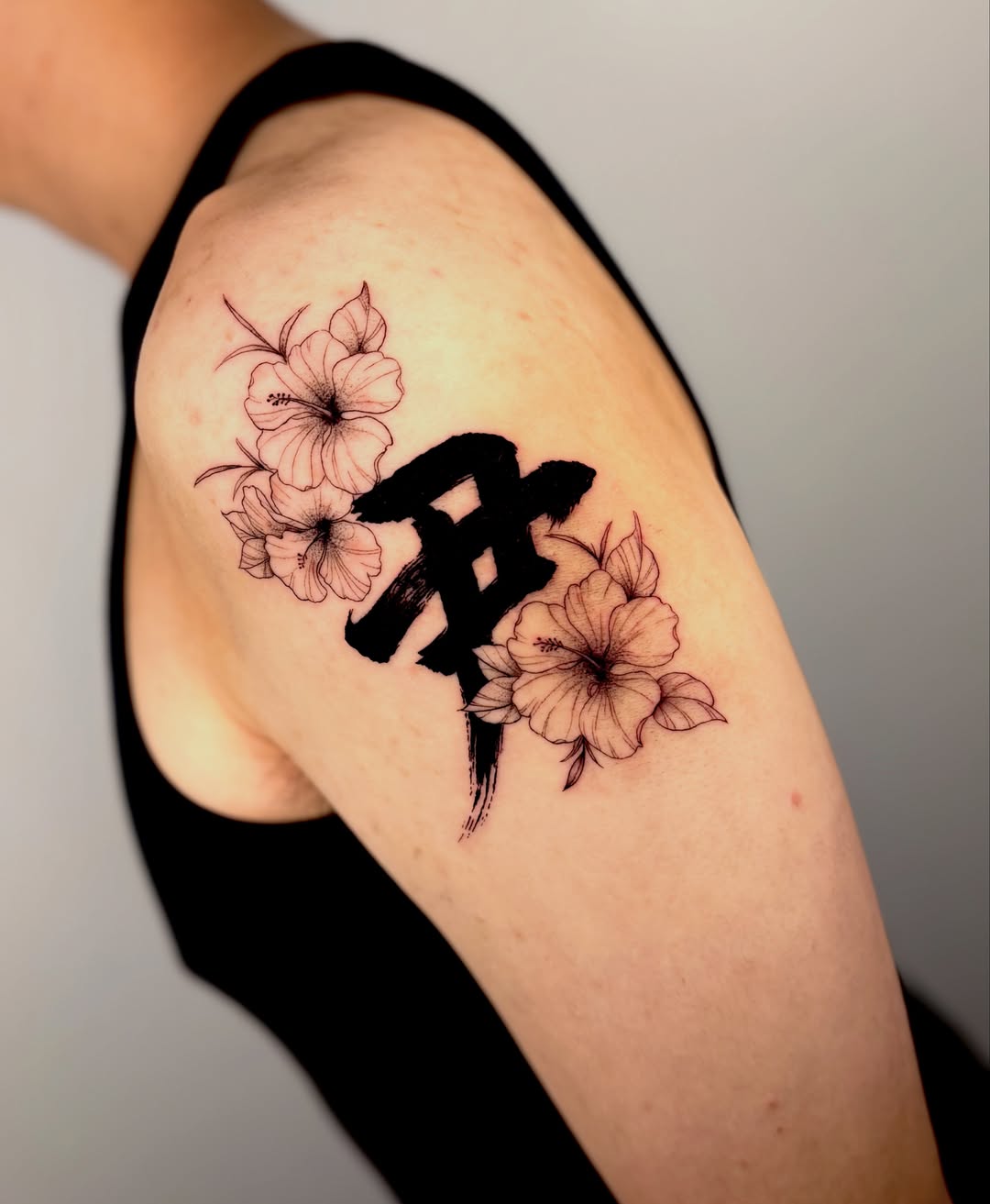 Hibiscus flowers and kanji black and grey tattoo on the shoulder by Orca