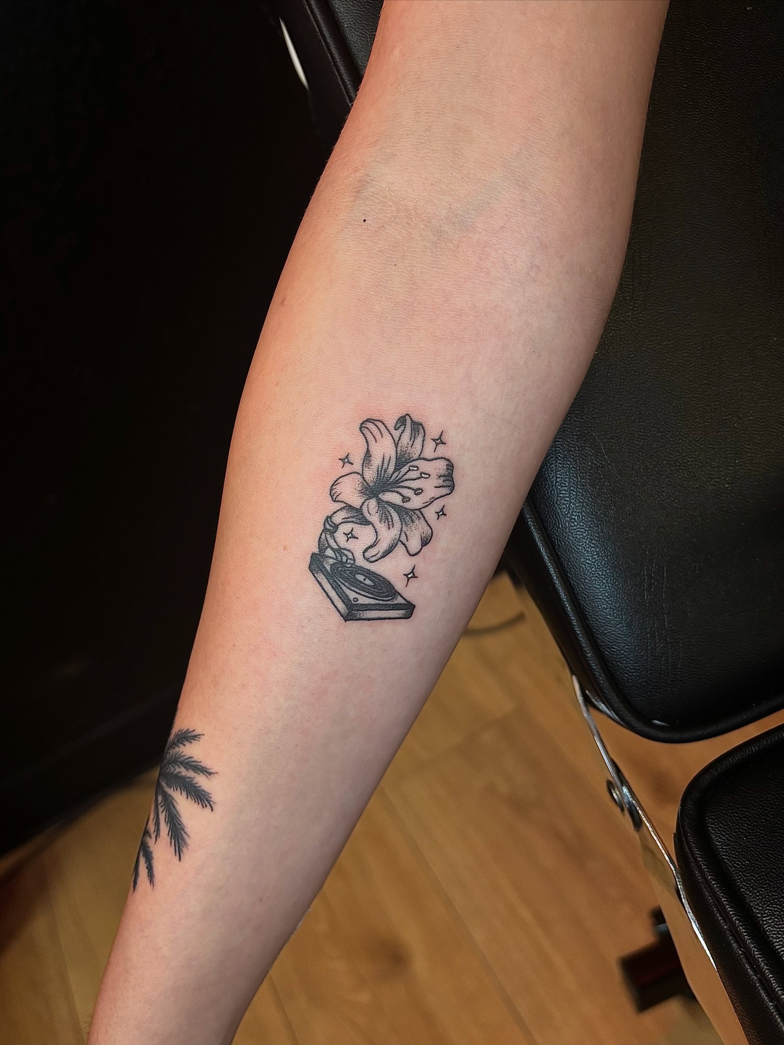 Lily and book black and grey tattoo on the forearm by JT.tattoos
