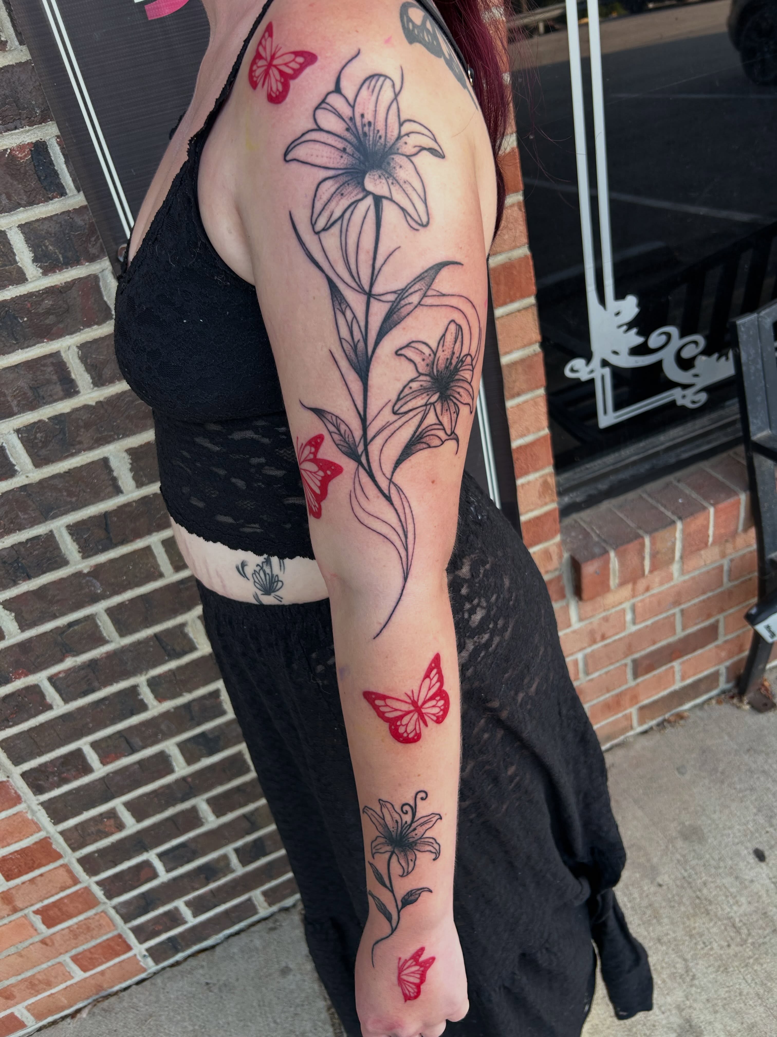Lily and butterfly black and grey tattoo on the forearm by Zach Andrews
