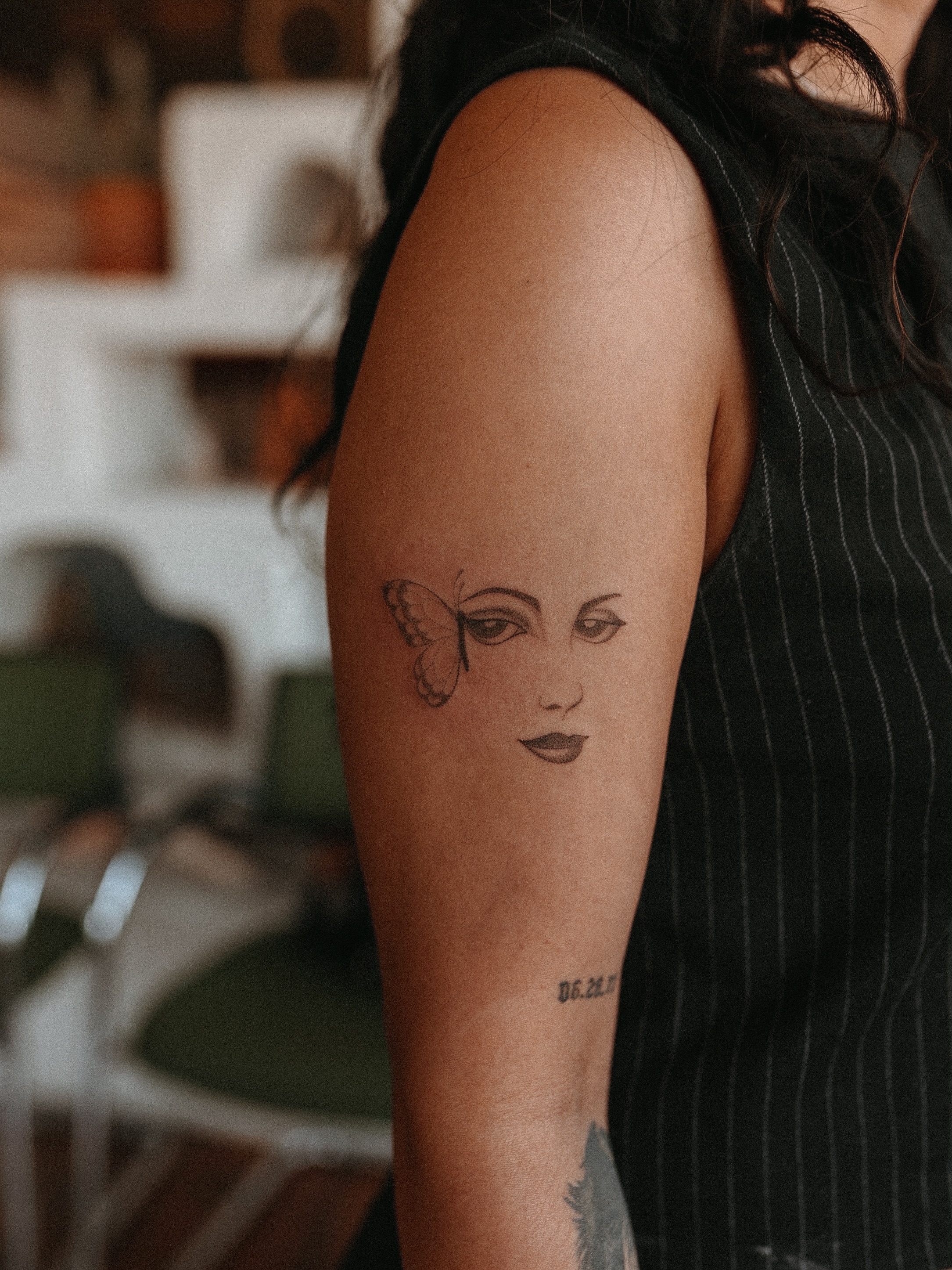 Woman's face with butterfly realism tattoo on the forearm by Grace Wise - Handpoke Tattoos