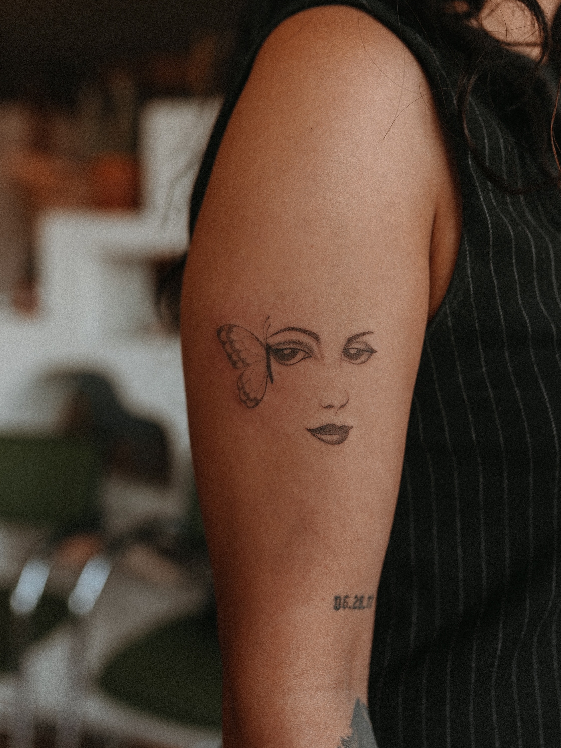 Woman's face with butterfly realism tattoo on the forearm by Grace Wise - Handpoke Tattoos