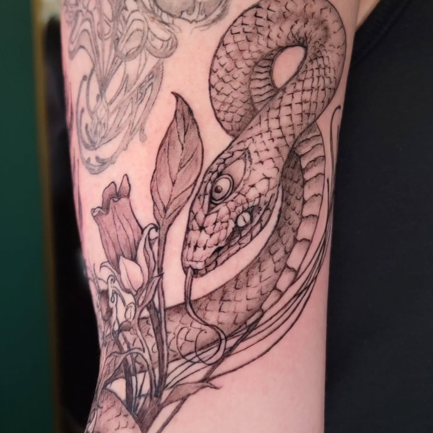 Snake and flowers realism tattoo on the forearm by Nathan Harkins-Oberbeck