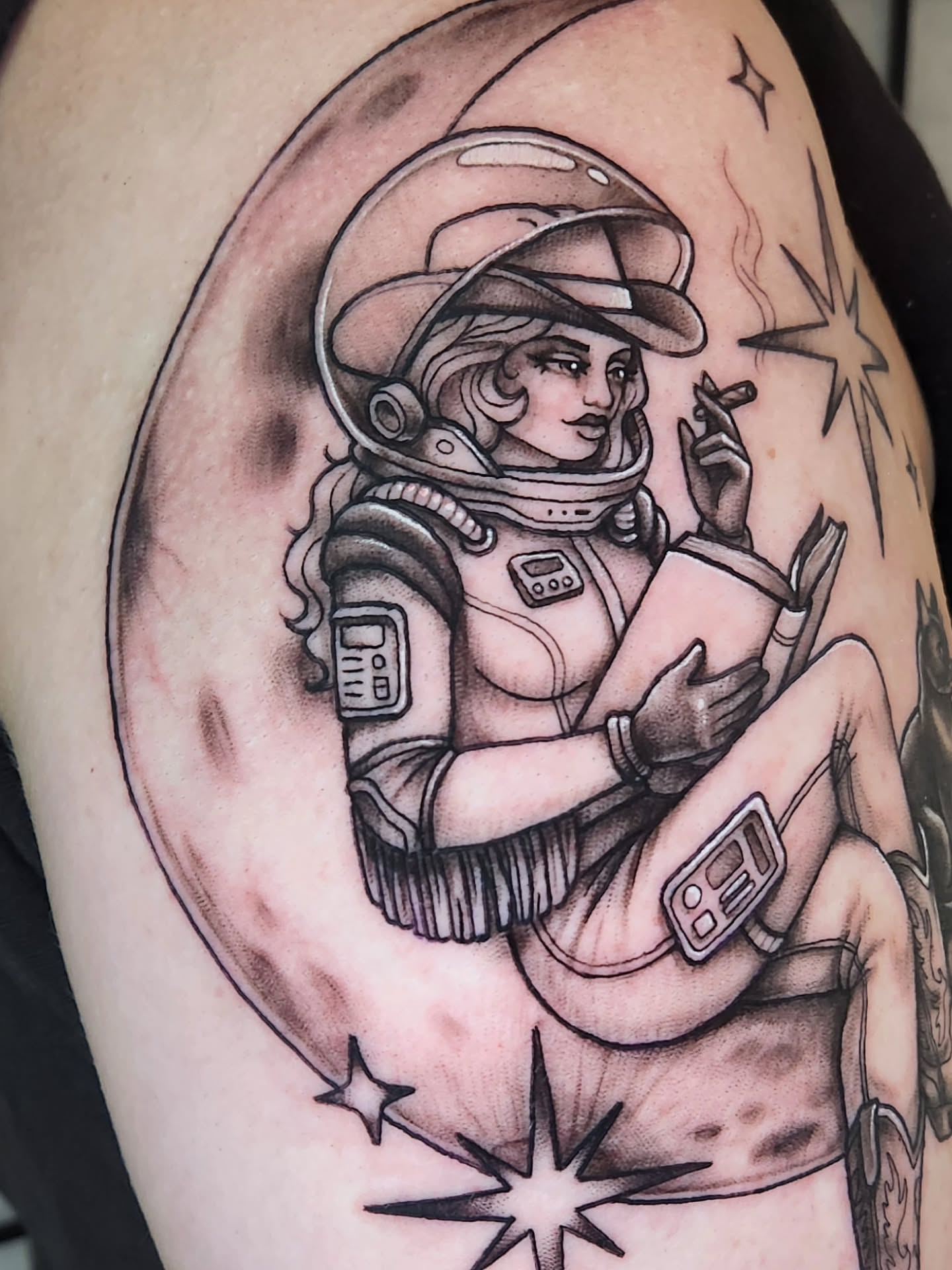 Astronaut reading realism tattoo on the shoulder by Amanda Boyd - Duh!