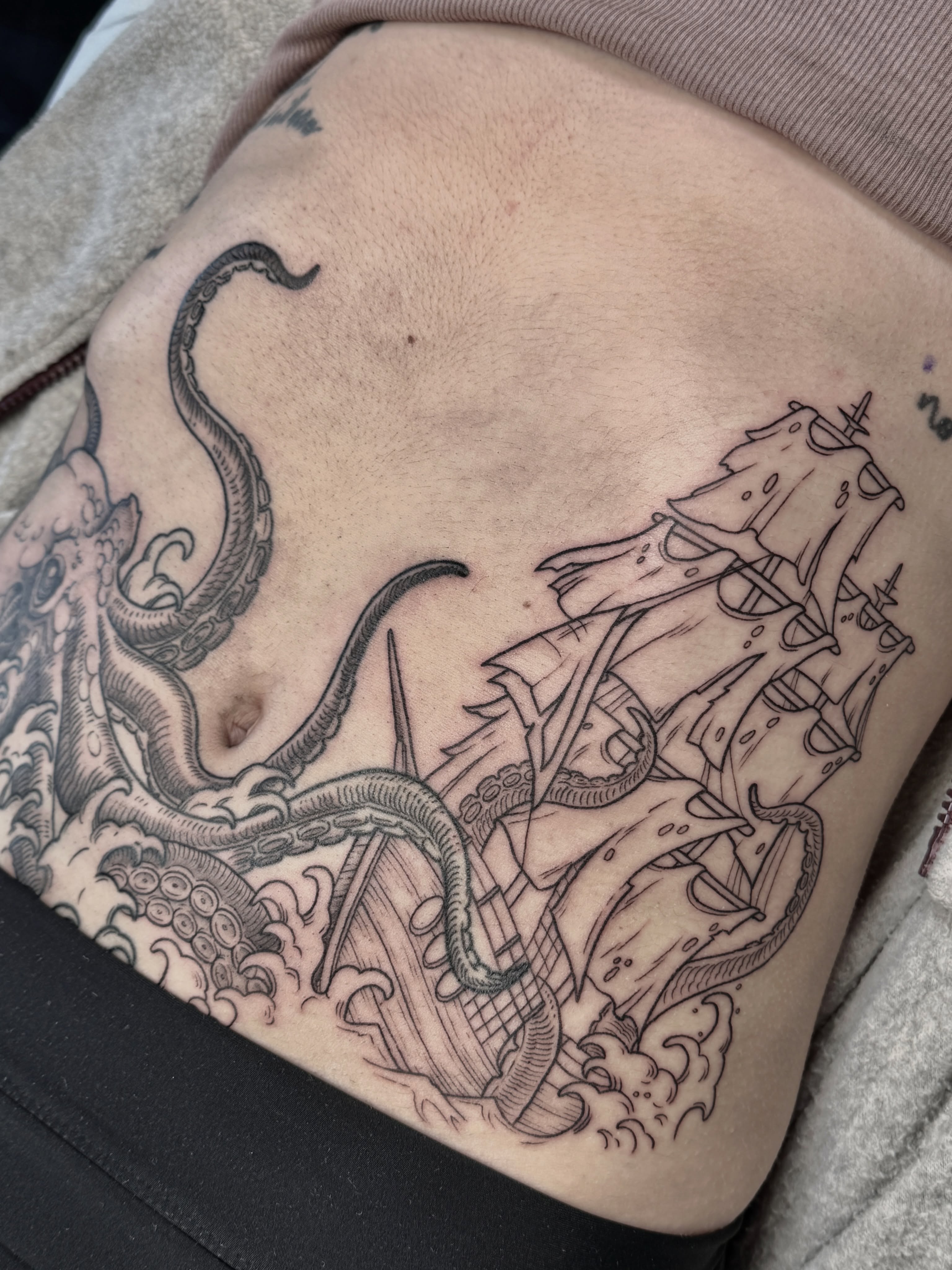Kraken attacking ship black and grey tattoo on the thigh by Hannah May, La Mesa, California