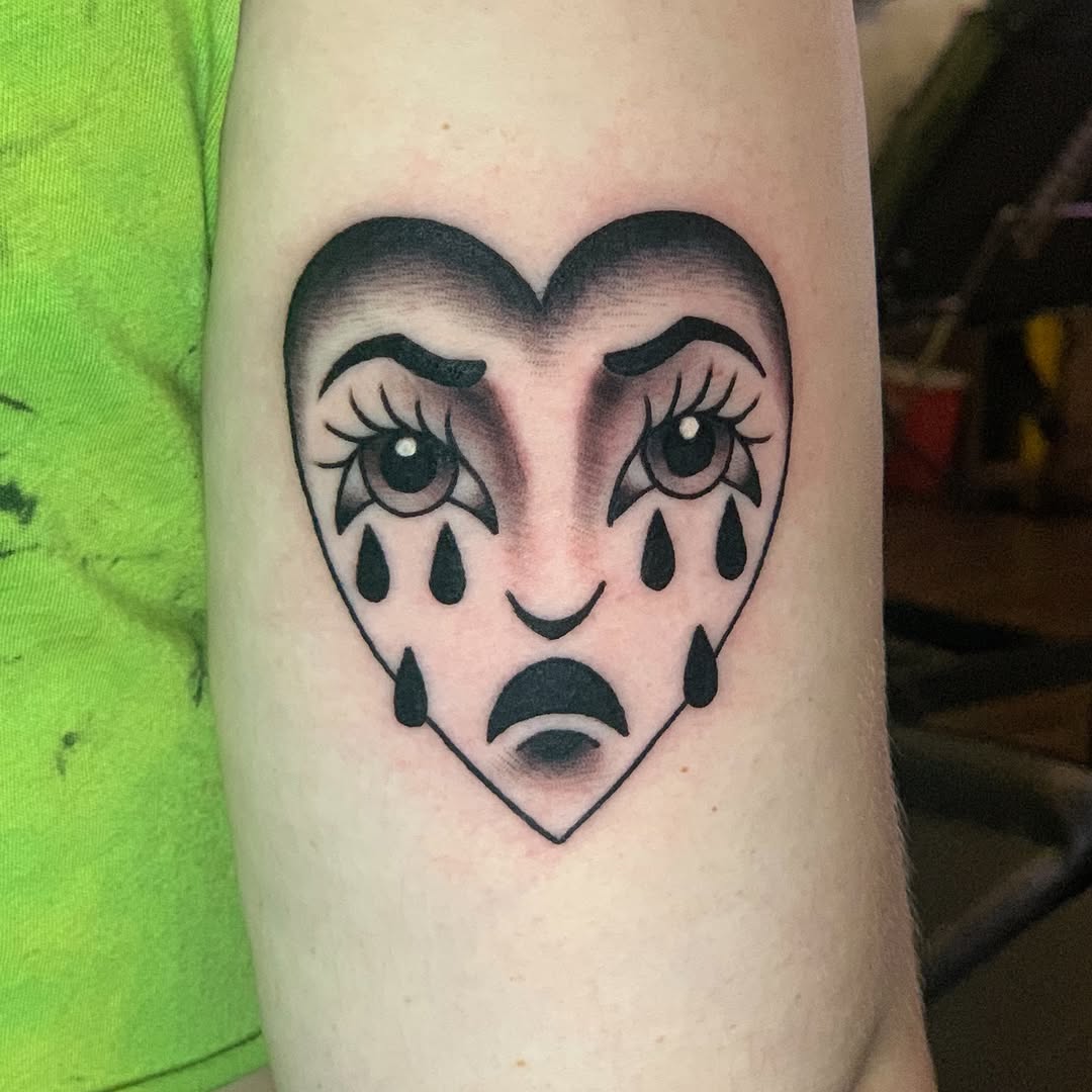 Sad heart face surrealism tattoo on the forearm by Olivia Marie